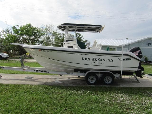 1999 Boston Whaler 23 Outrage boat on trailer, parked on grass.