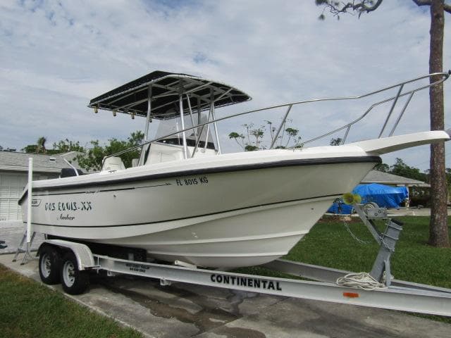 1999 Boston Whaler 23 Outrage boat on trailer, parked outdoors.