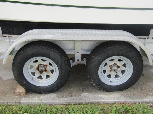 Trailer wheels for 1999 Boston Whaler 23 Outrage boat on concrete surface.