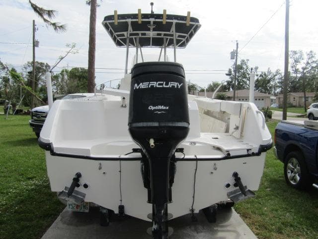 1999 Boston Whaler 23 Outrage boat with Mercury OptiMax engine, parked outdoors.