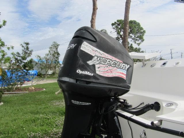 1999 Boston Whaler 23 Outrage with Mercury OptiMax outboard motor in a grassy yard.