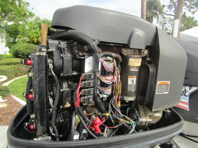 Close-up of a 1999 Boston Whaler 23 Outrage boat engine with visible wiring and components.