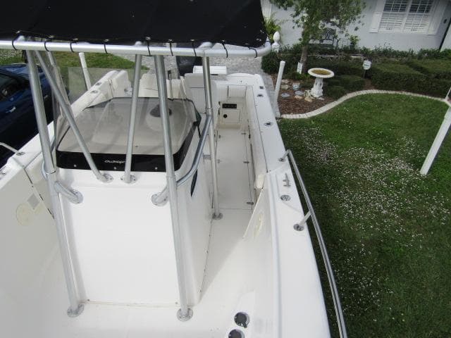 1999 Boston Whaler 23 Outrage boat with T-top, parked on grass.