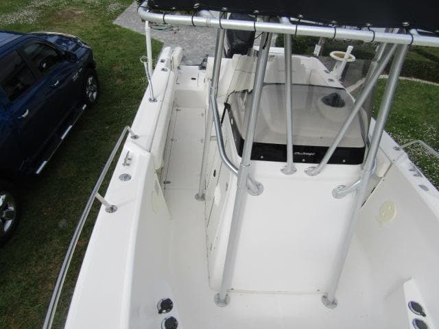 1999 Boston Whaler 23 Outrage boat with center console and T-top, parked beside a blue vehicle.