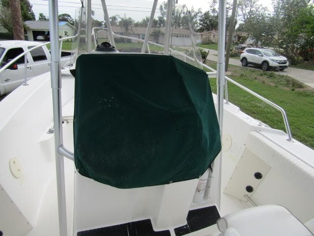1999 Boston Whaler 23 Outrage boat with green console cover, parked outdoors.