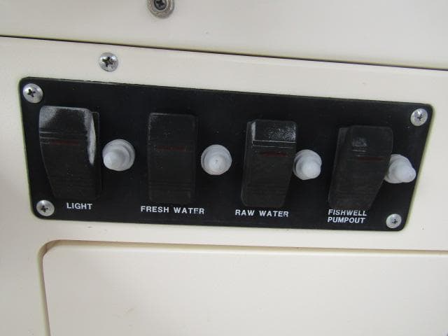 Control panel on a 1999 Boston Whaler 23 Outrage boat with labeled switches.