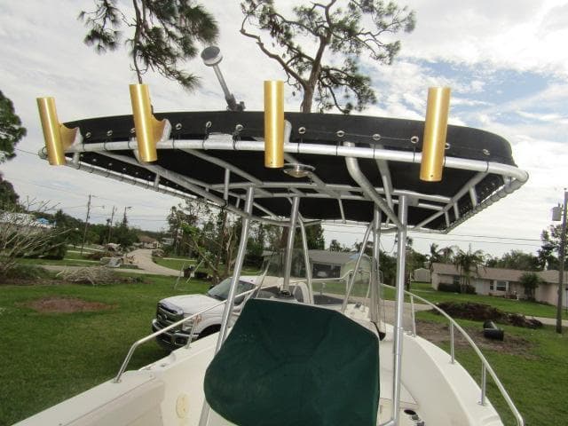 1999 Boston Whaler 23 Outrage boat with T-top and rod holders, parked outdoors.