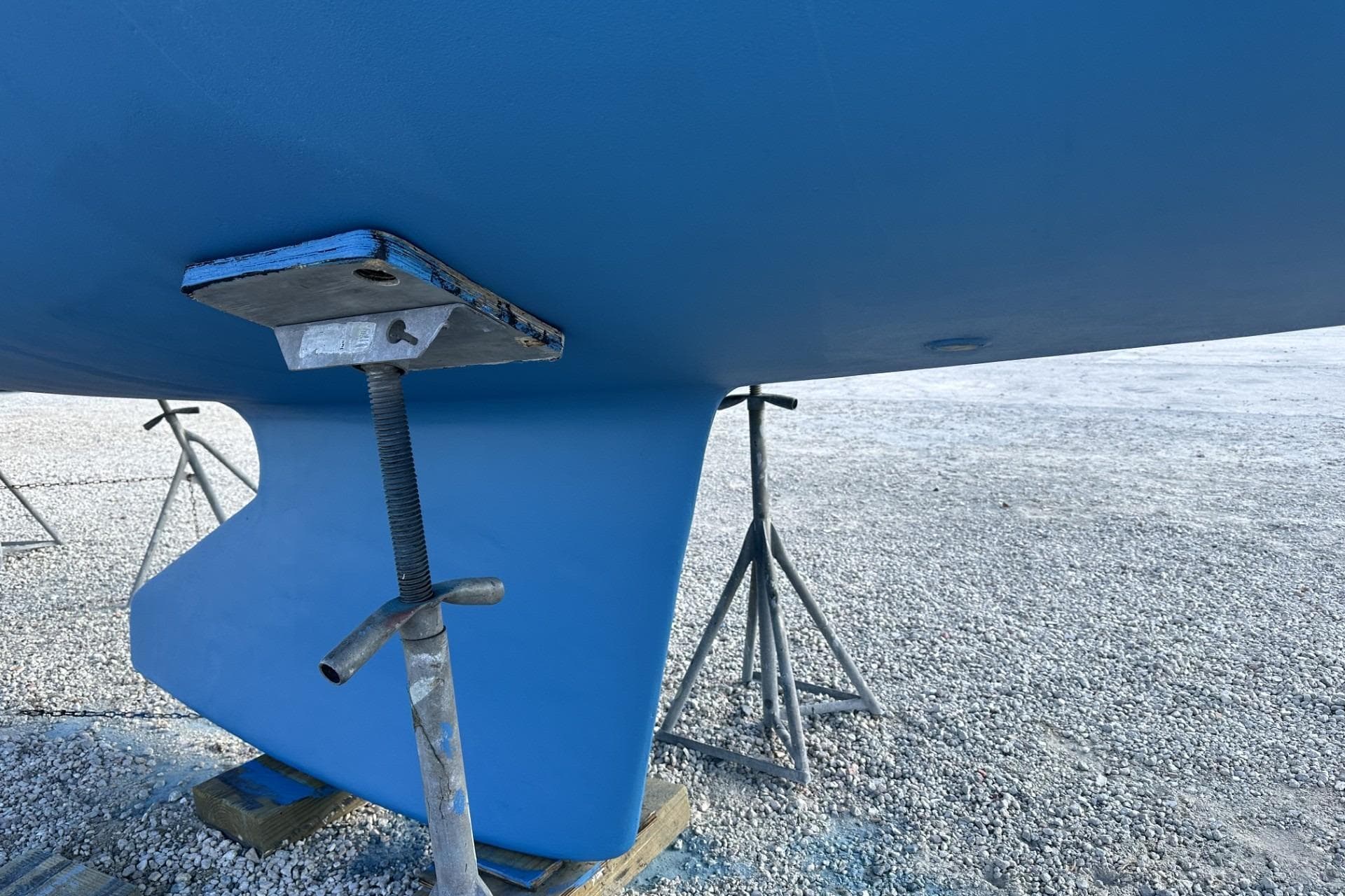 2004 J Boats J/32 sailboat keel on stands, resting on gravel surface.