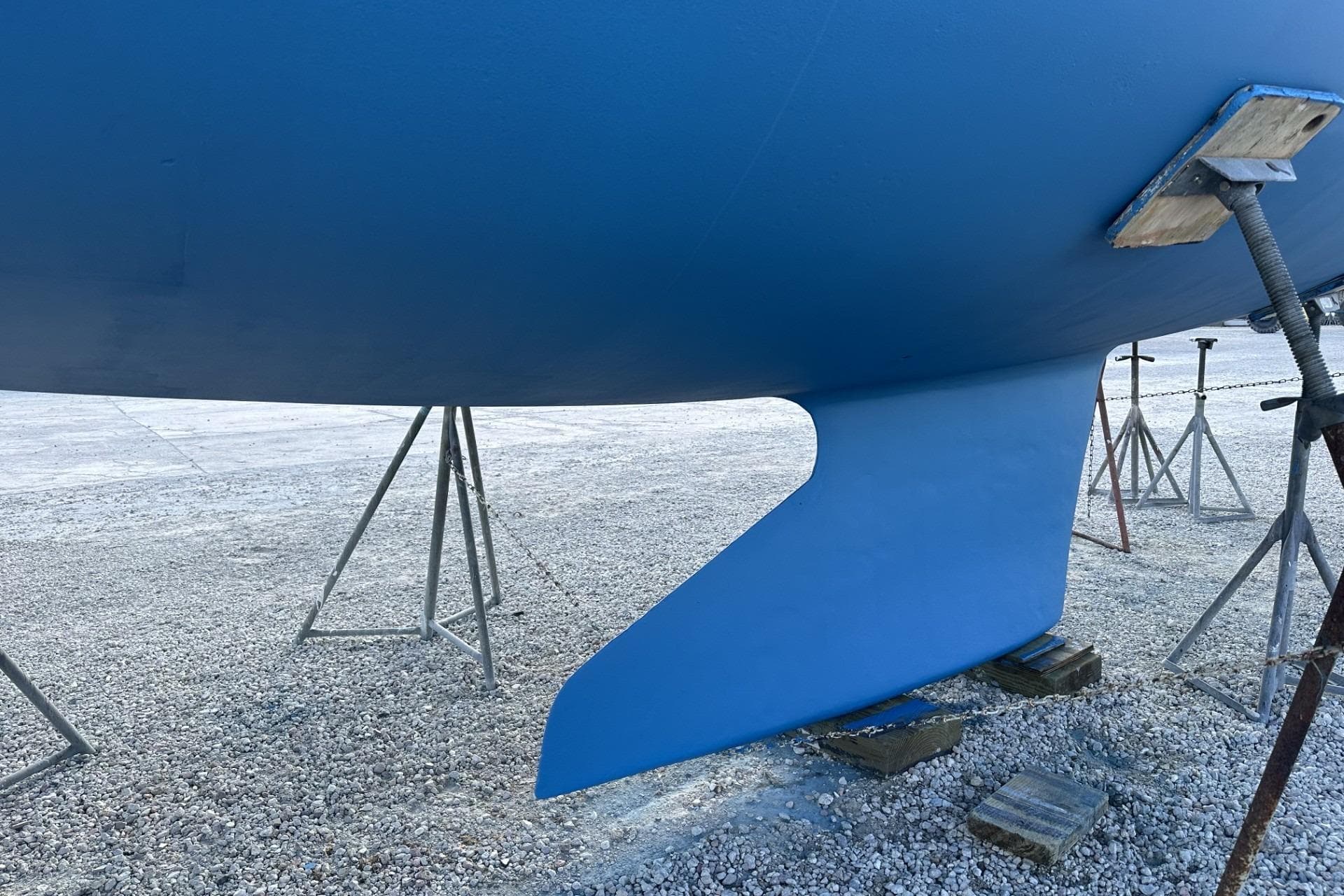 2004 J Boats J/32 sailboat keel on stands, displayed on gravel surface.