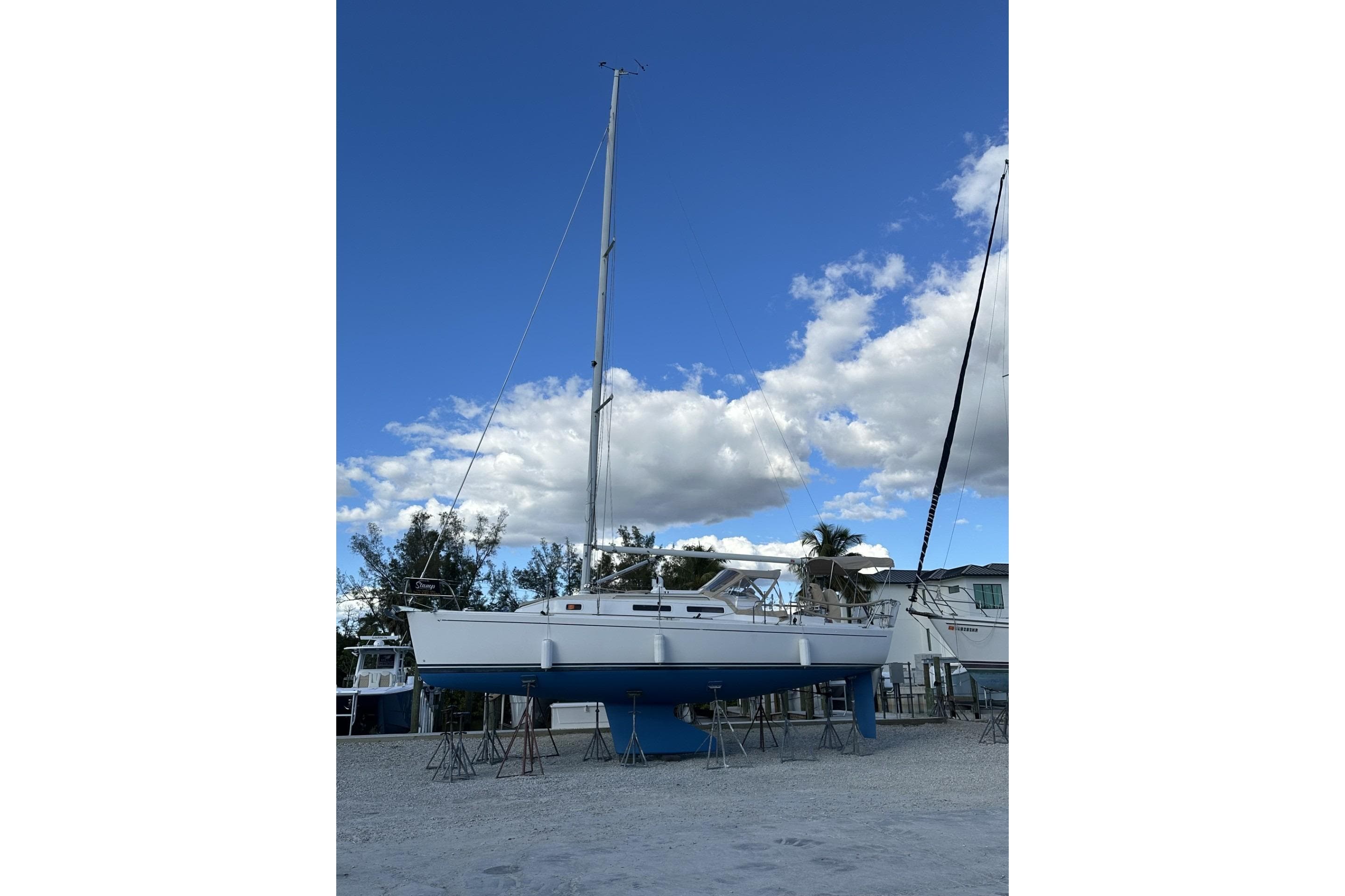 2004 J Boats J/32 sailboat on stands, clear sky background.