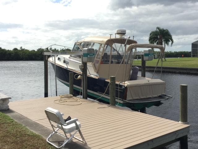2002 Legacy Yachts 28 Express docked by a serene waterfront with a chair on the pier.