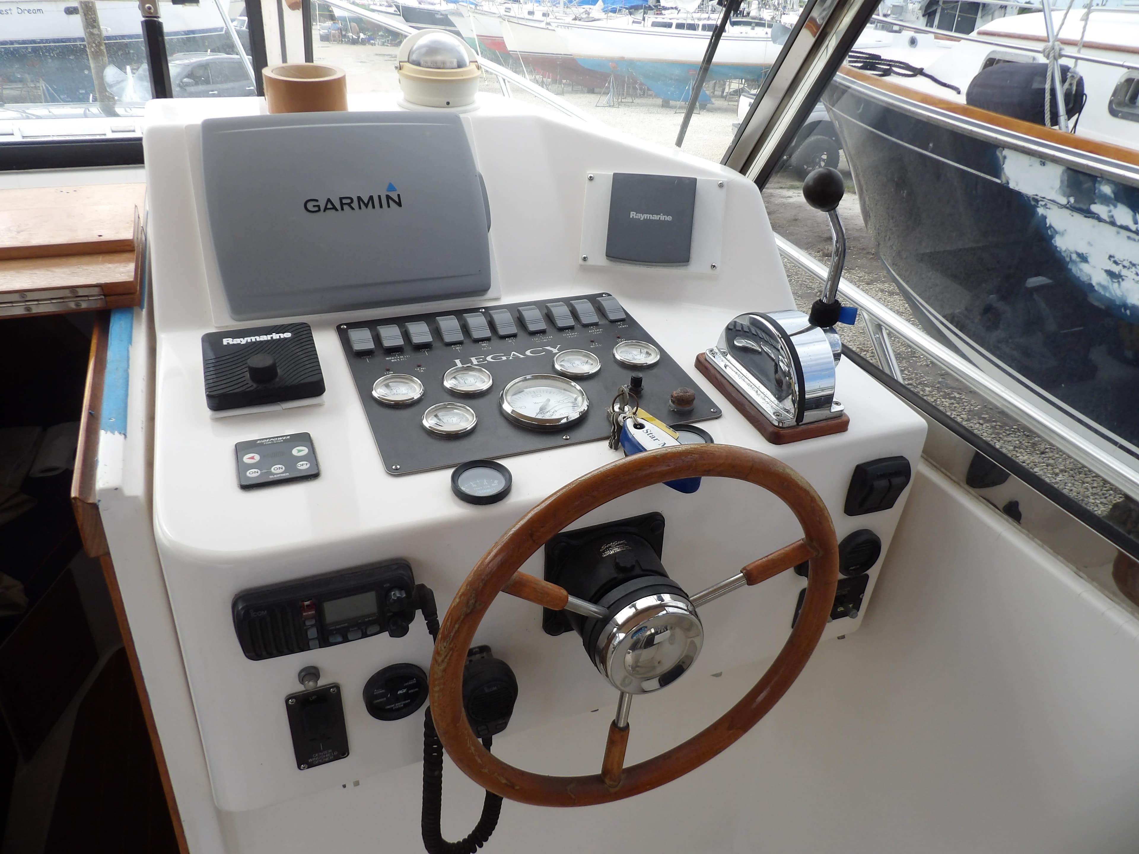 Helm of 2002 Legacy Yachts 28 Express with Garmin navigation and wooden steering wheel.