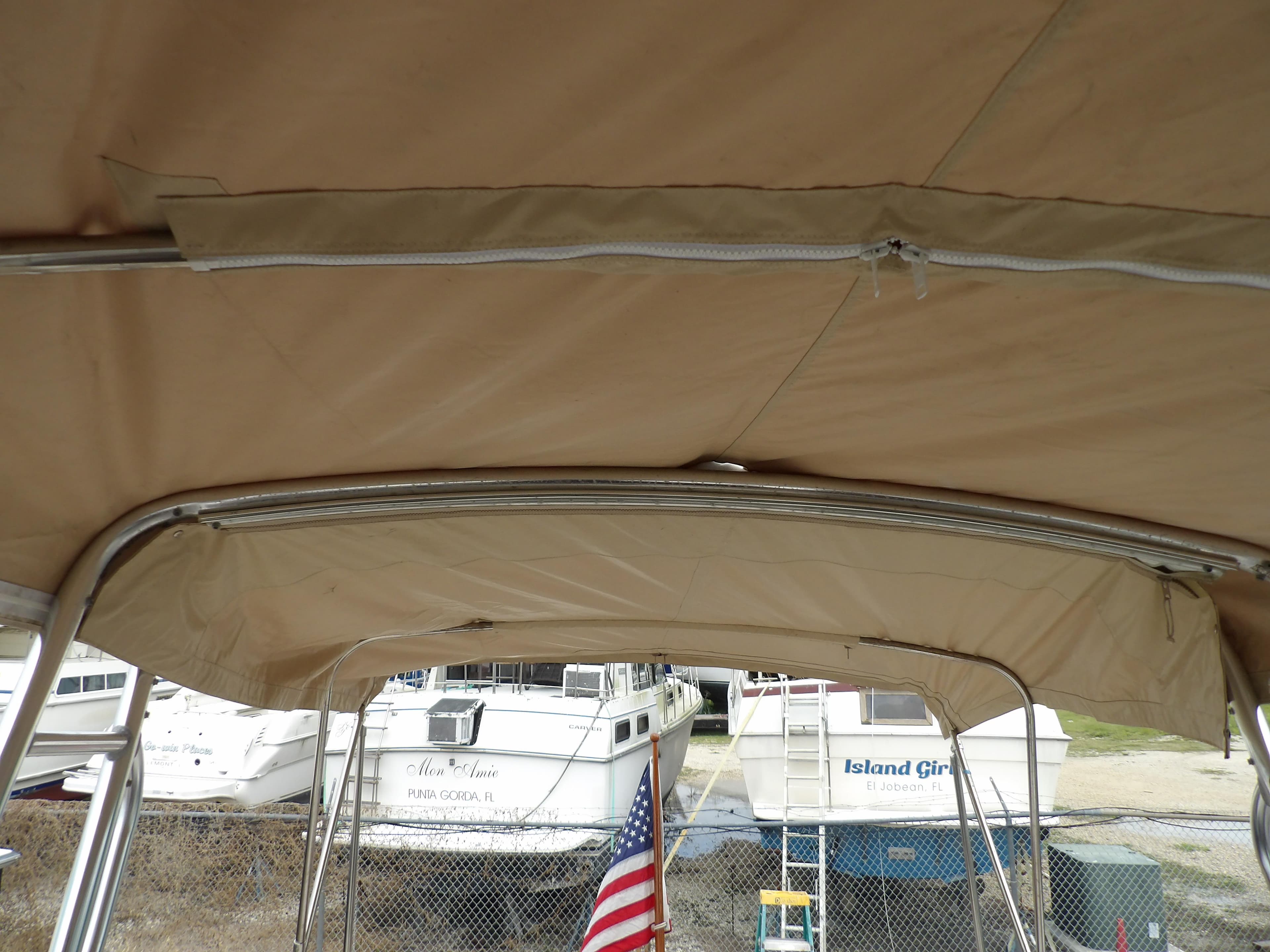 2002 Legacy Yachts 28 Express with beige canopy, docked near other boats.