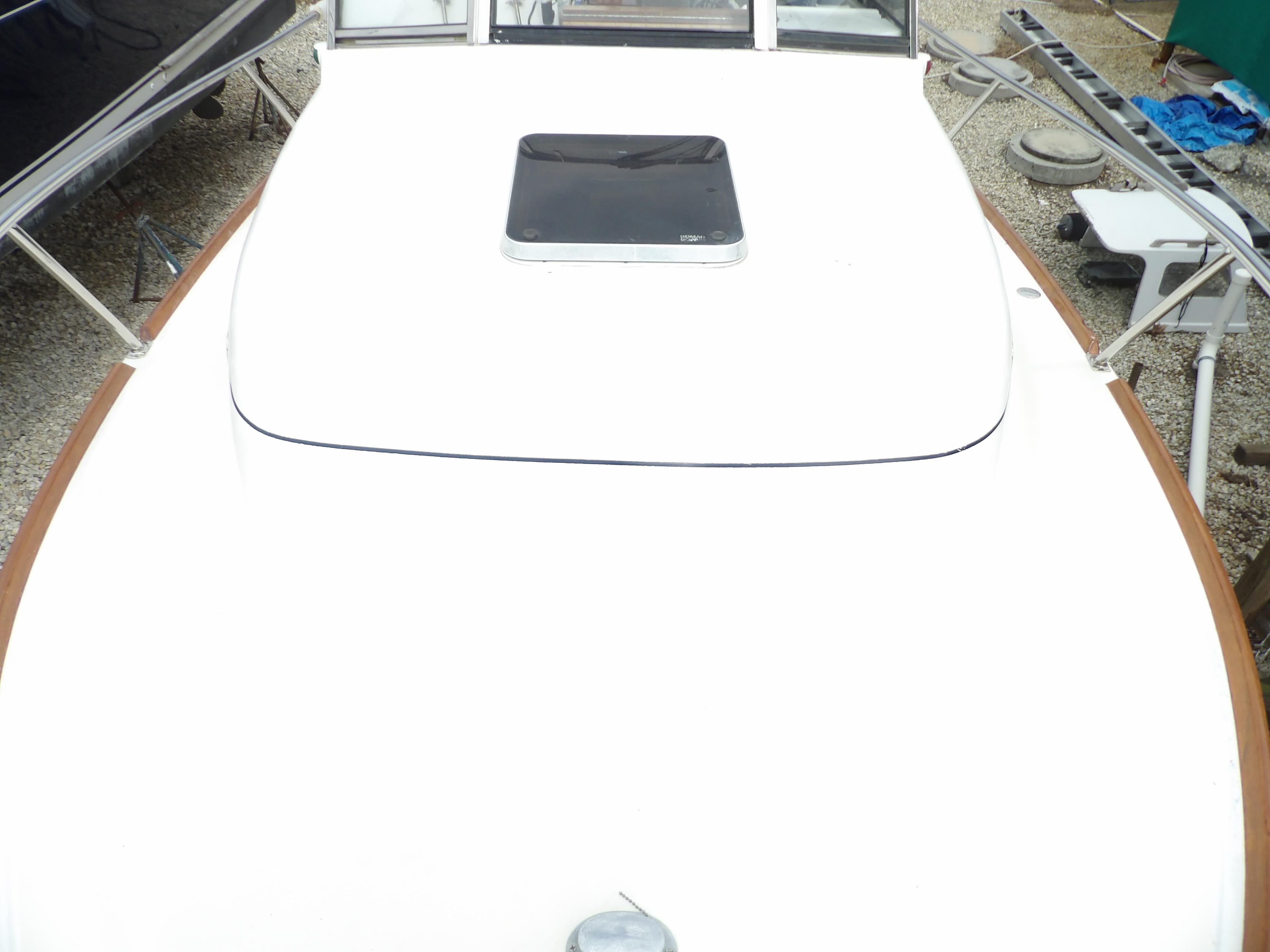 2002 Legacy Yachts 28 Express boat deck with hatch, docked on gravel.