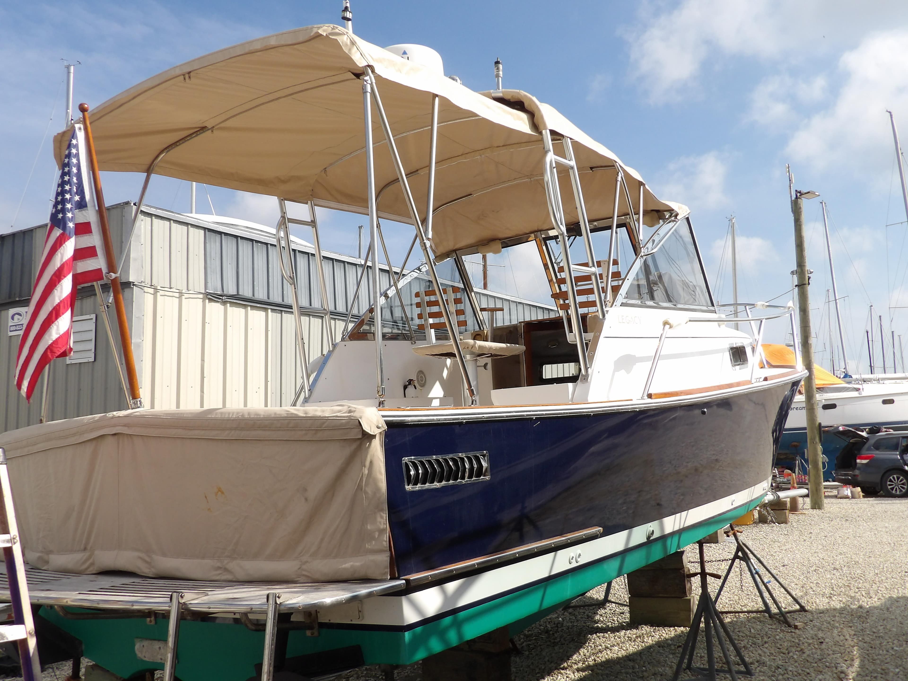 2002 Legacy Yachts 28 Express boat with canopy, docked on land, American flag displayed.