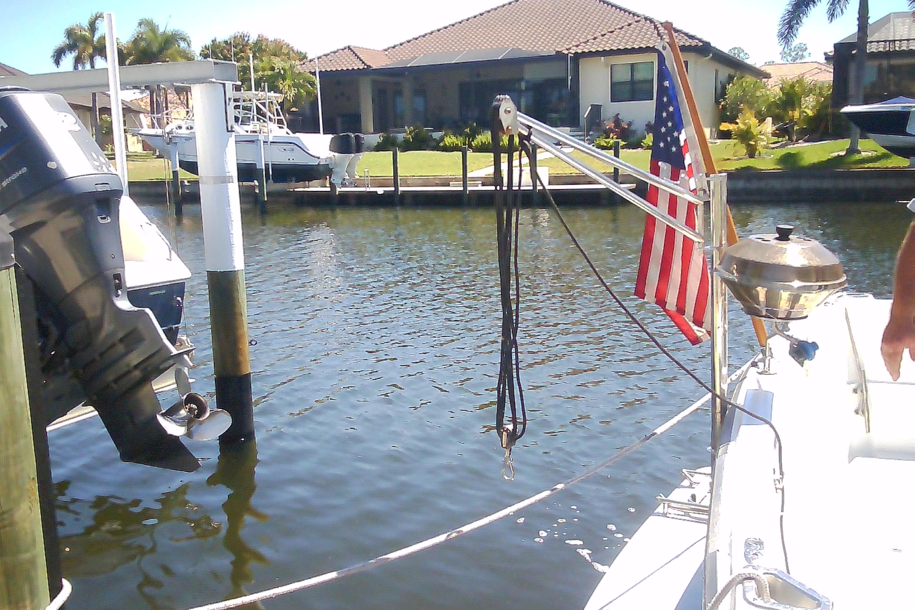 Boat docked by waterfront home, featuring American flag and grill, Sabre 34, 1999 model.