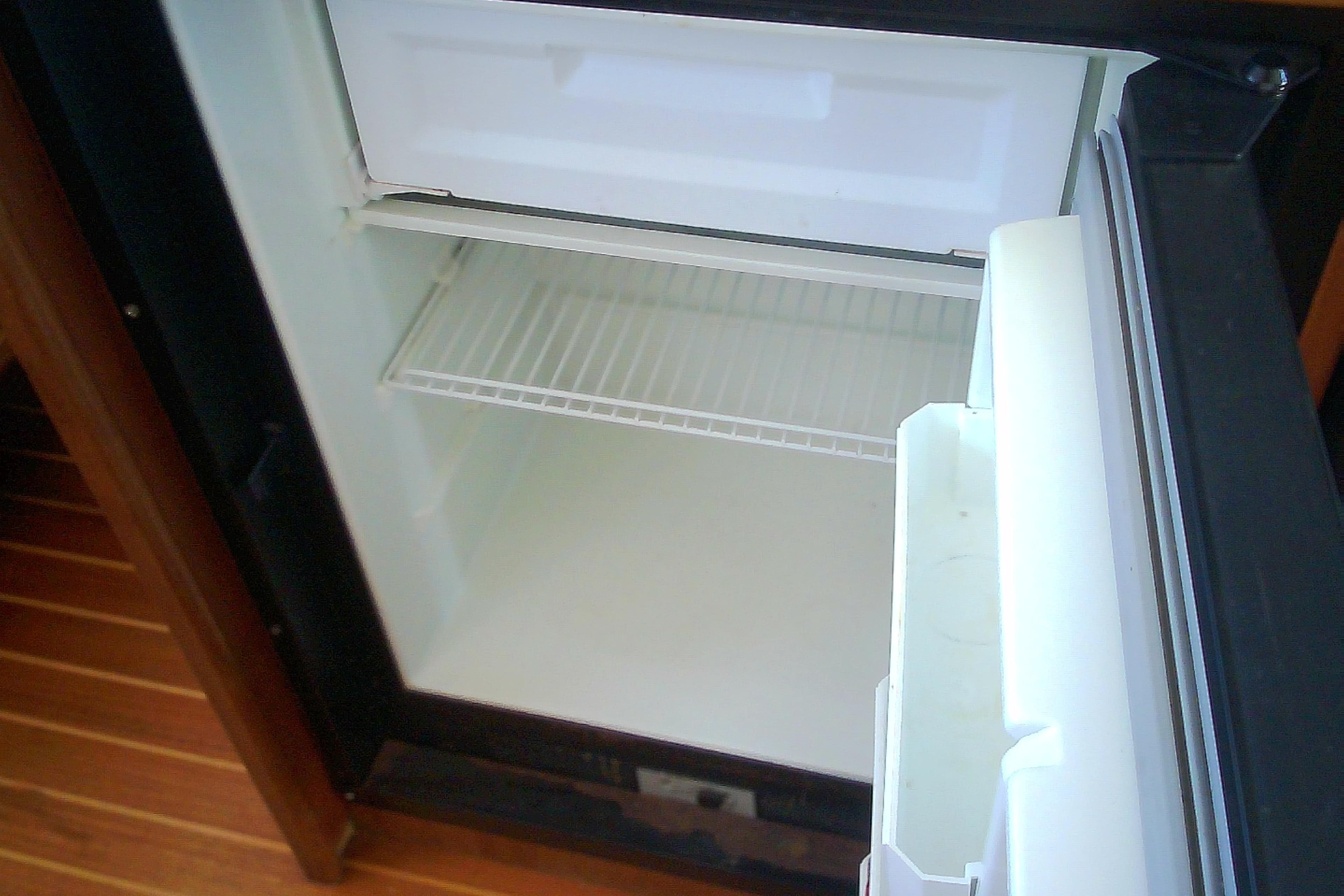 Open refrigerator inside a 1999 Sabre 34 boat, showing empty shelves.