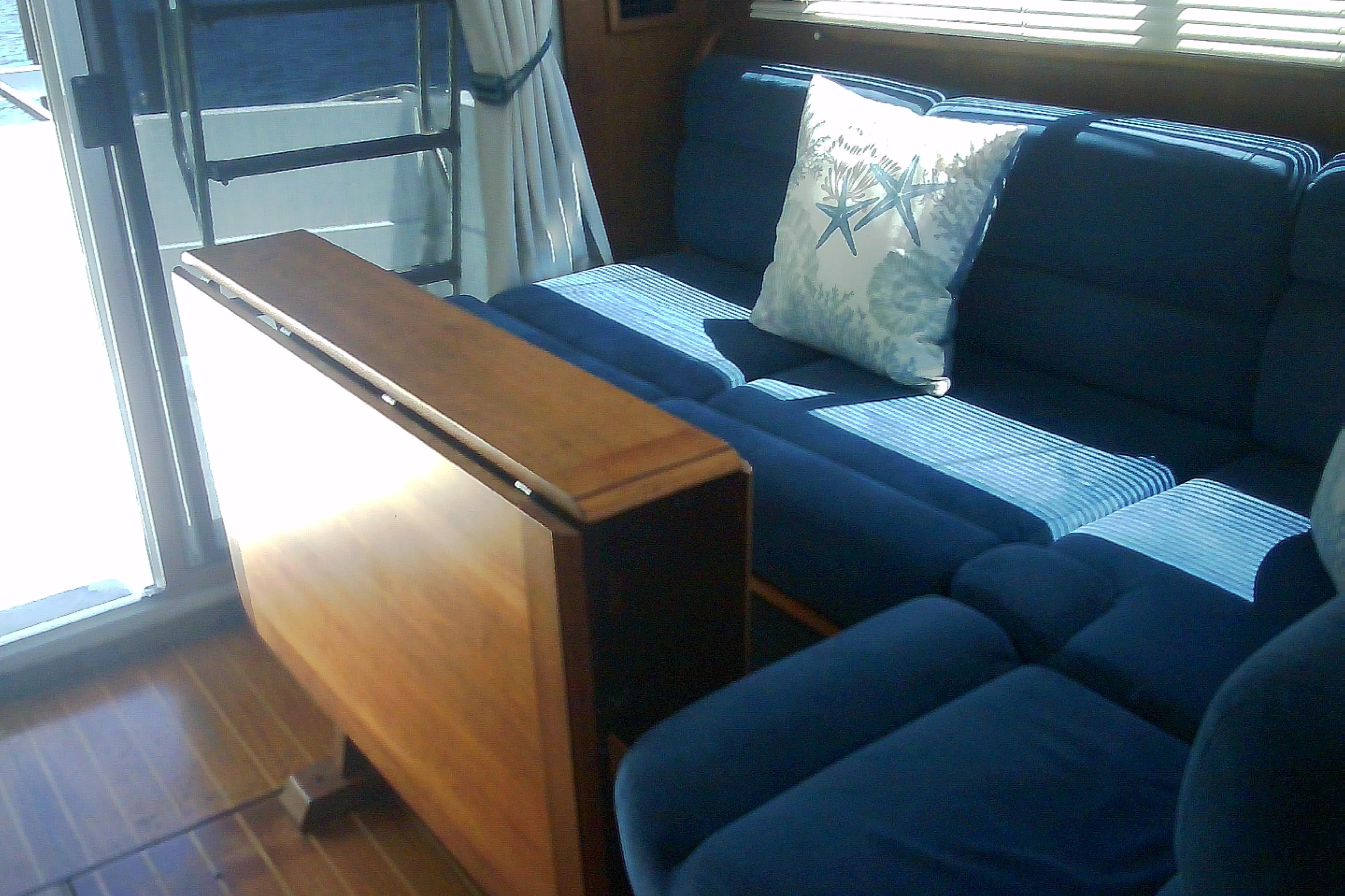 Interior of 1999 Sabre 34 yacht with blue sofa and nautical-themed pillow.