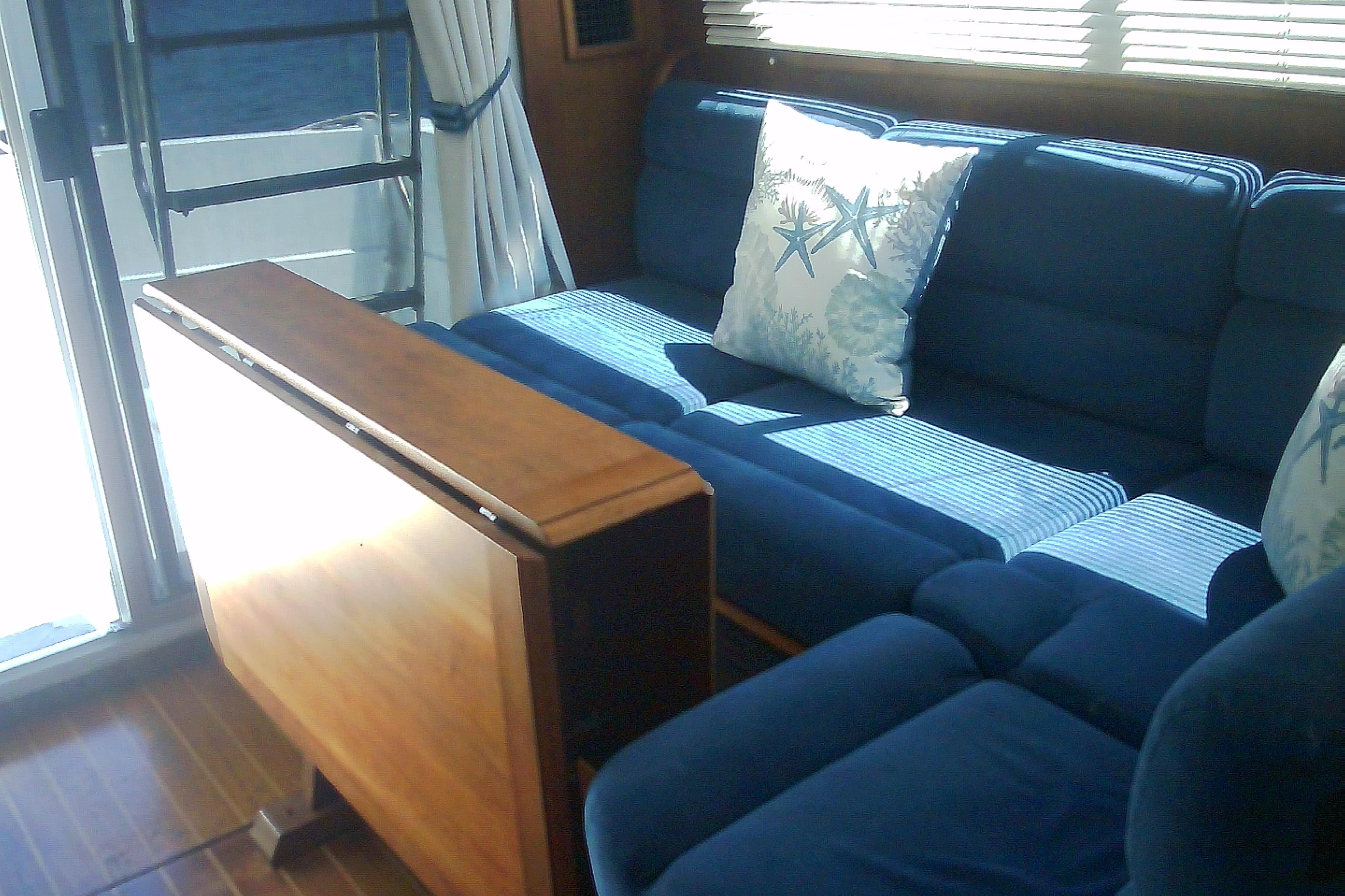 Interior of 1999 Sabre 34 yacht with blue sofa and nautical-themed pillows.