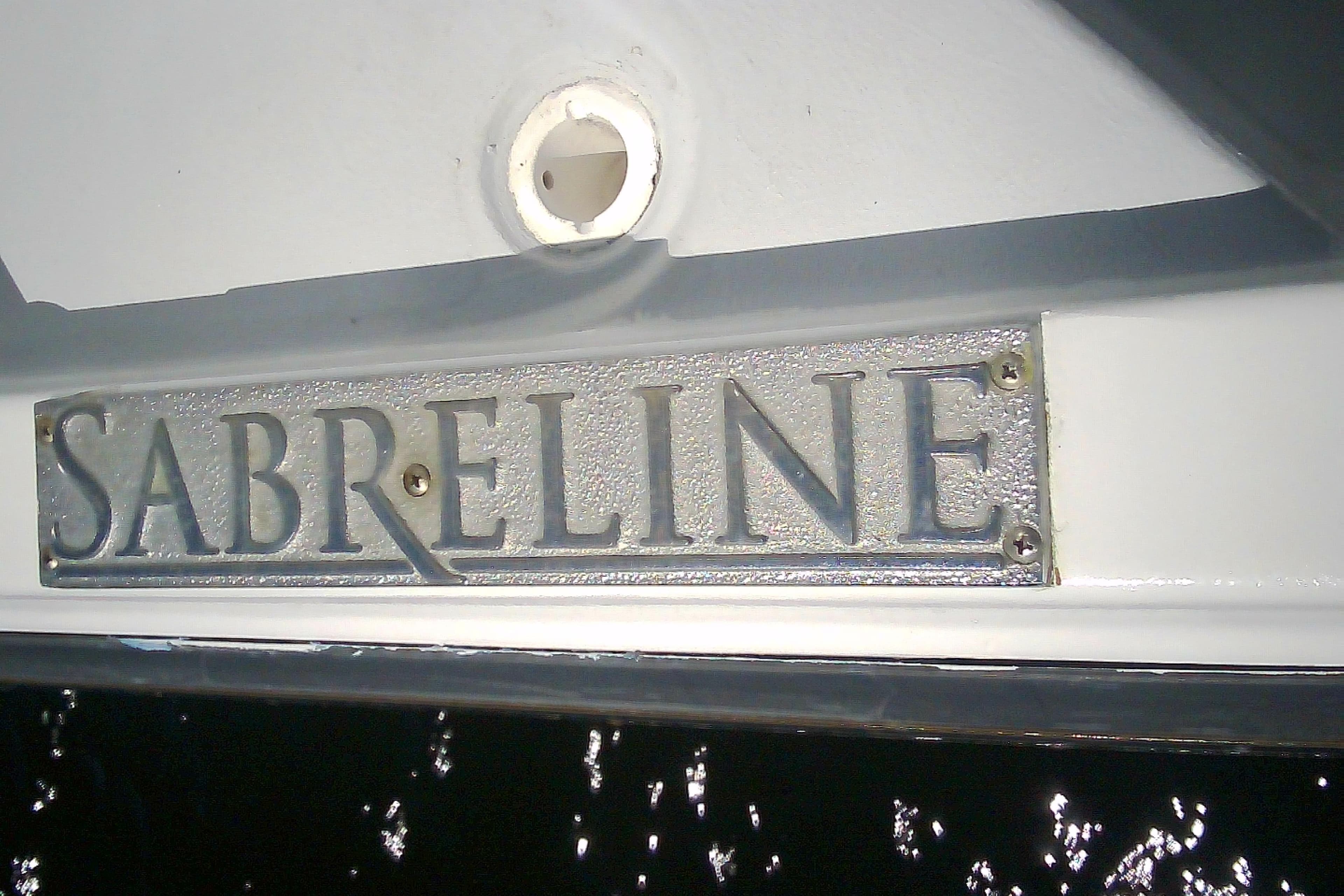 1999 Sabre 34 boat with "Sabreline" nameplate, reflecting sunlight on water.
