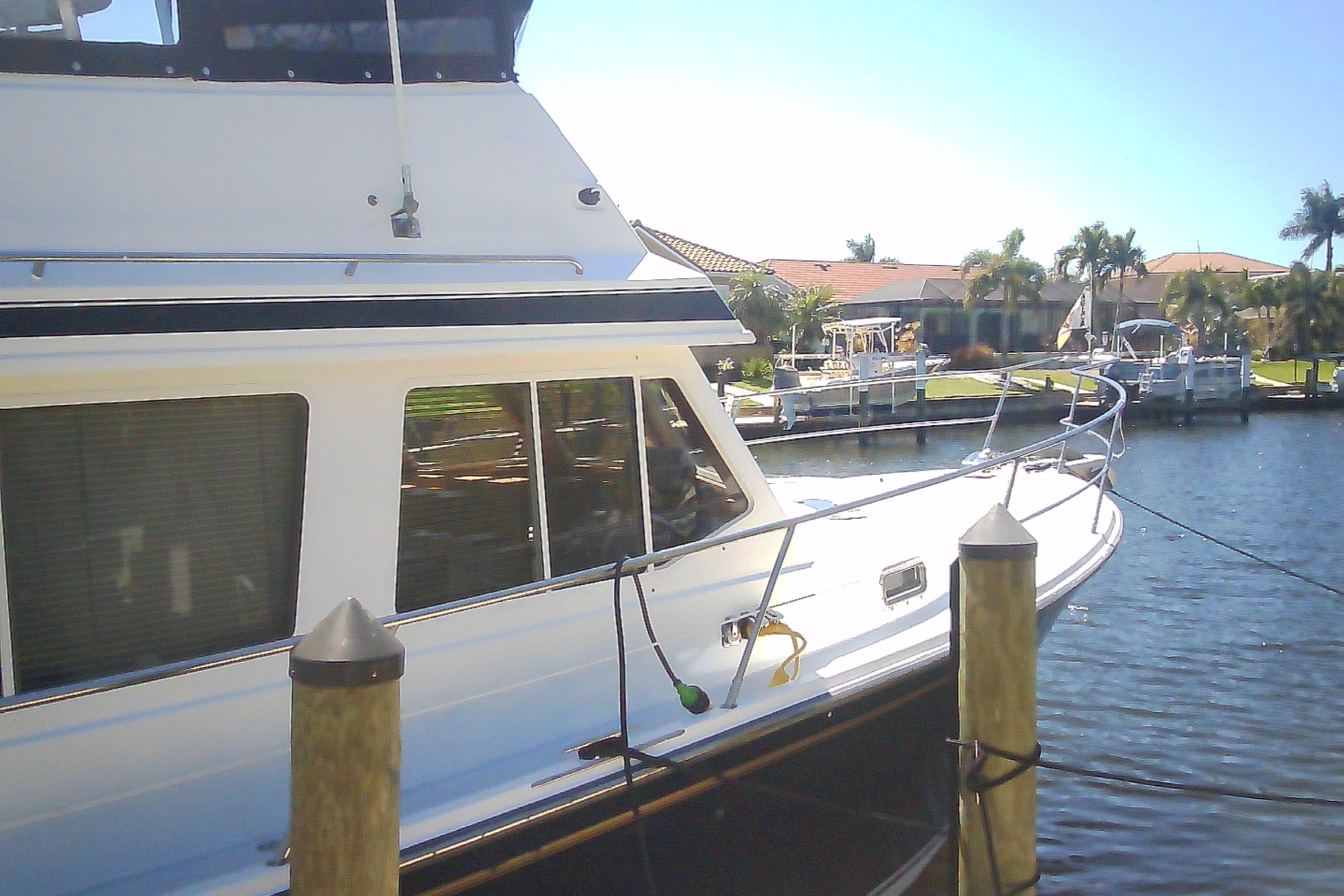 1999 Sabre 34 yacht docked by waterfront homes, sunny day, palm trees in background.