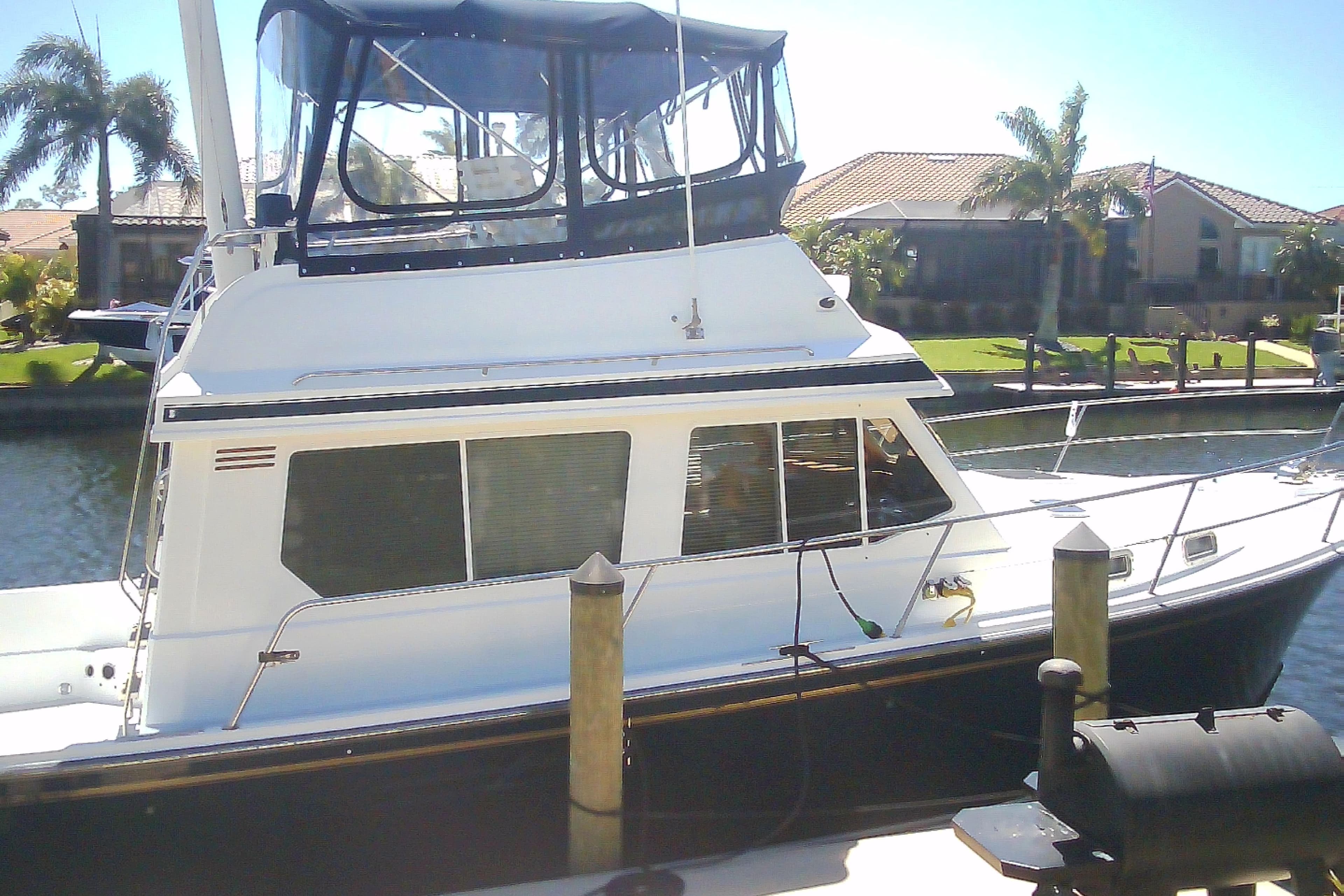 1999 Sabre 34 boat docked in sunny marina with palm trees.