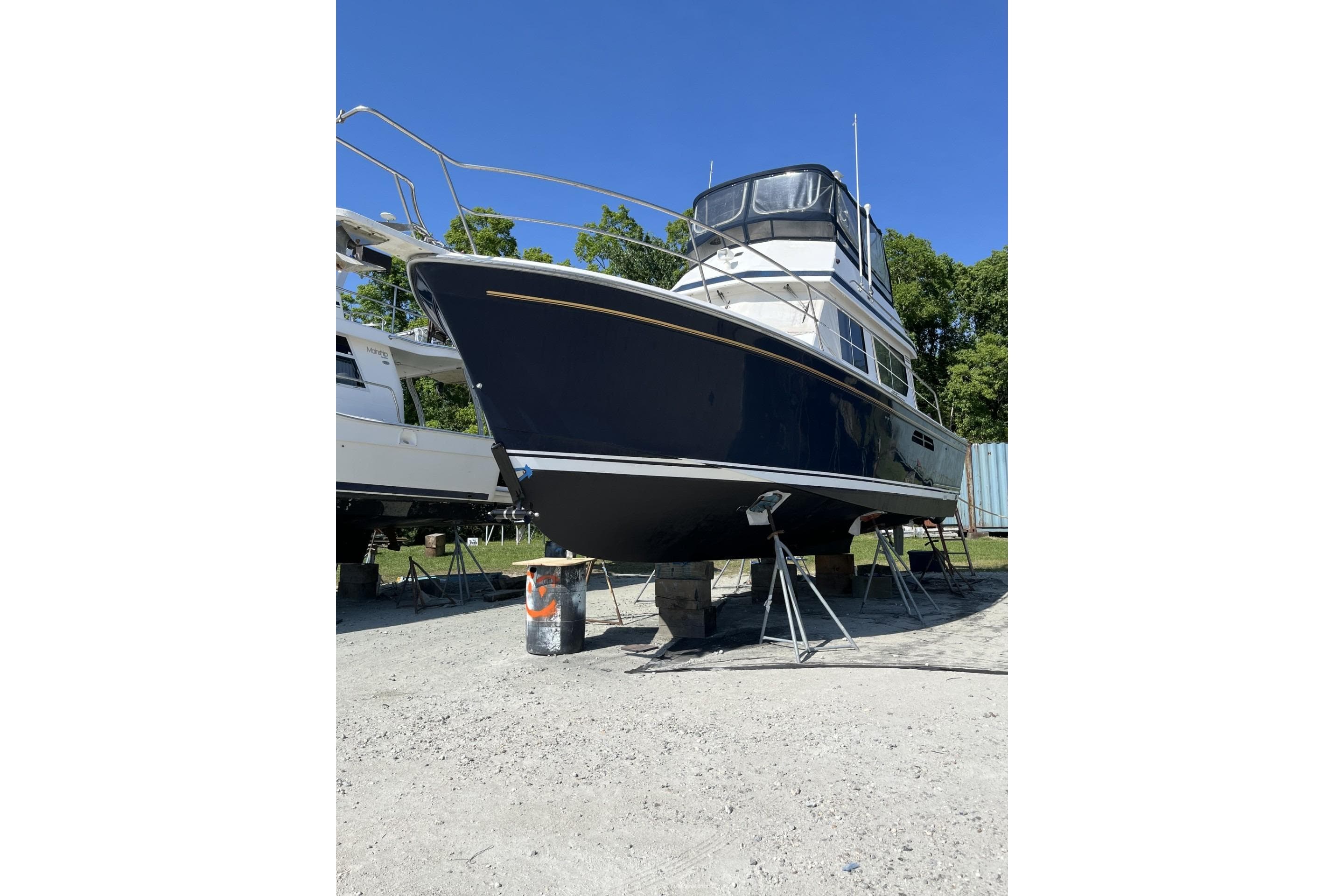 1999 Sabre 34 boat on stands, blue hull, clear sky background.