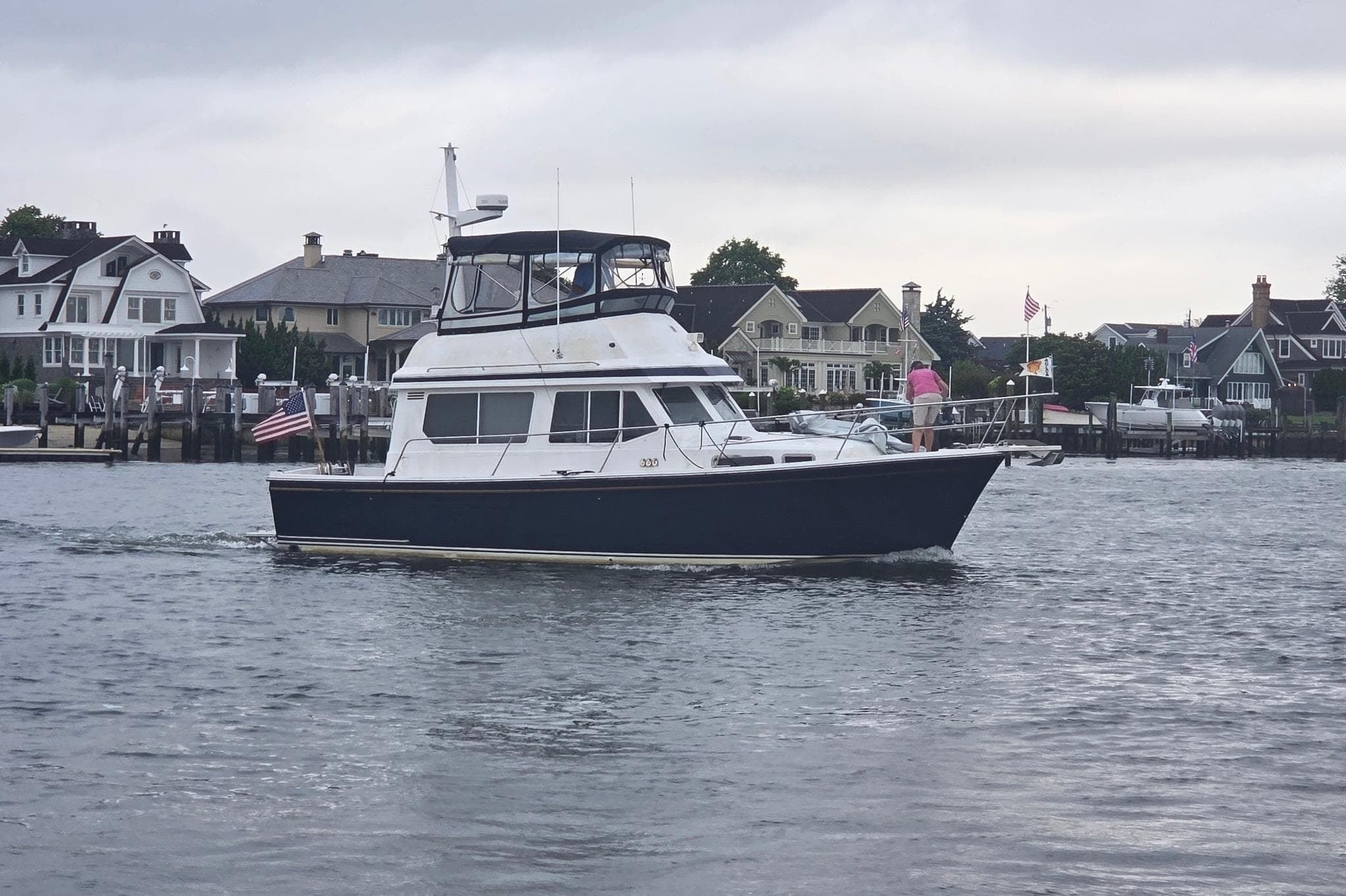 1999 Sabre 34 yacht cruising near waterfront homes on a cloudy day.