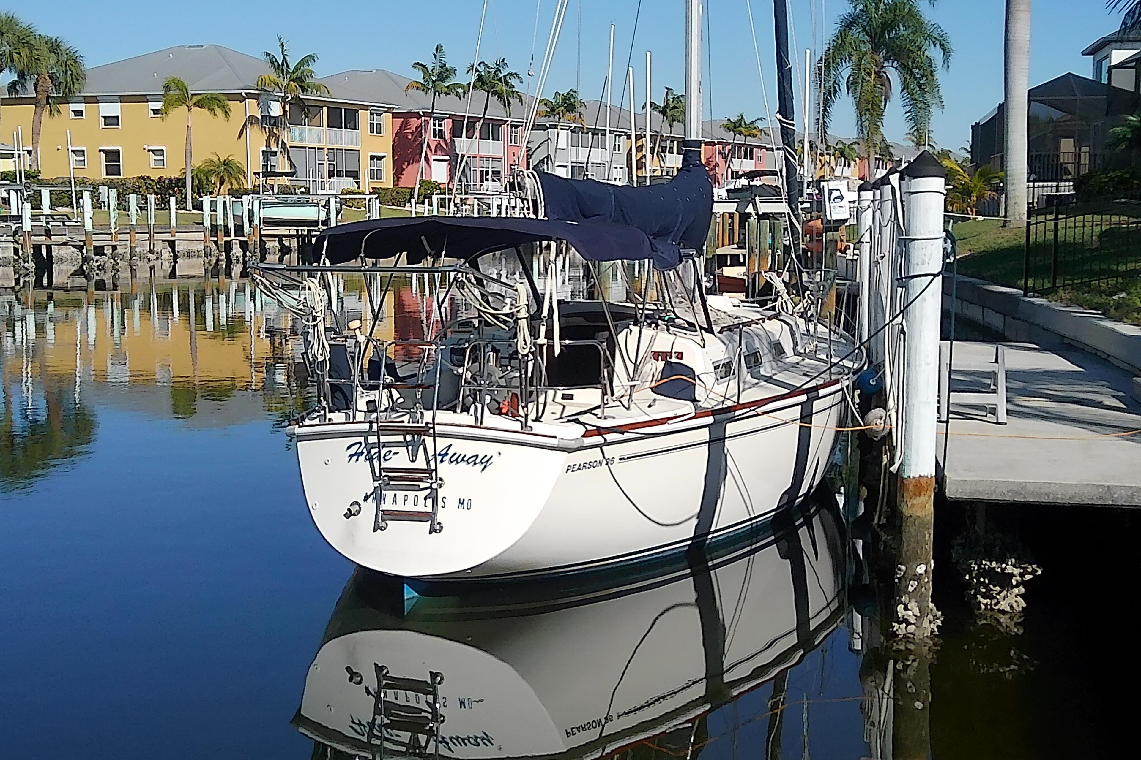 1988 Pearson 36-2 sailboat docked in a sunny marina with palm trees.