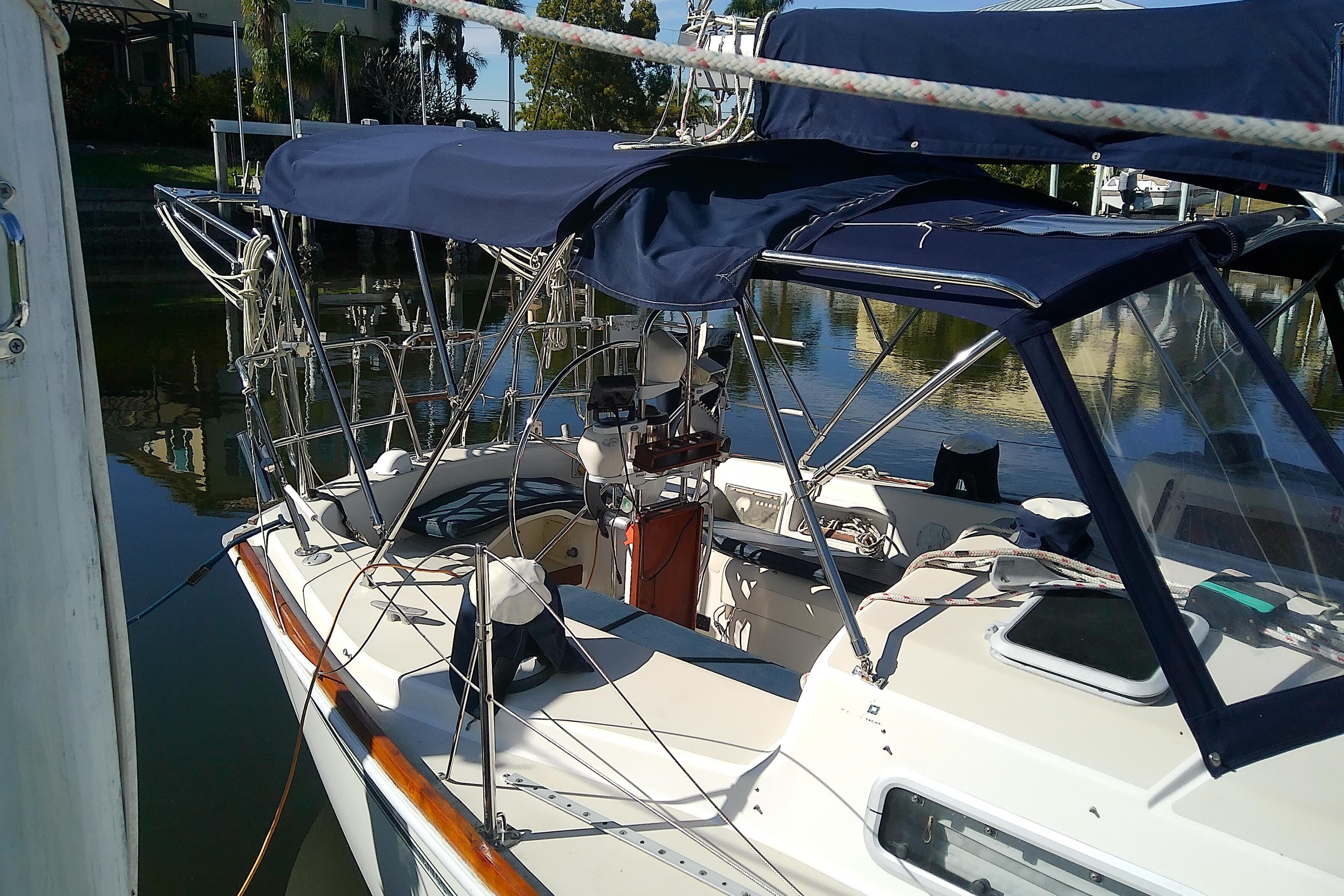 1988 Pearson 36-2 sailboat with blue canopy docked in a serene marina.