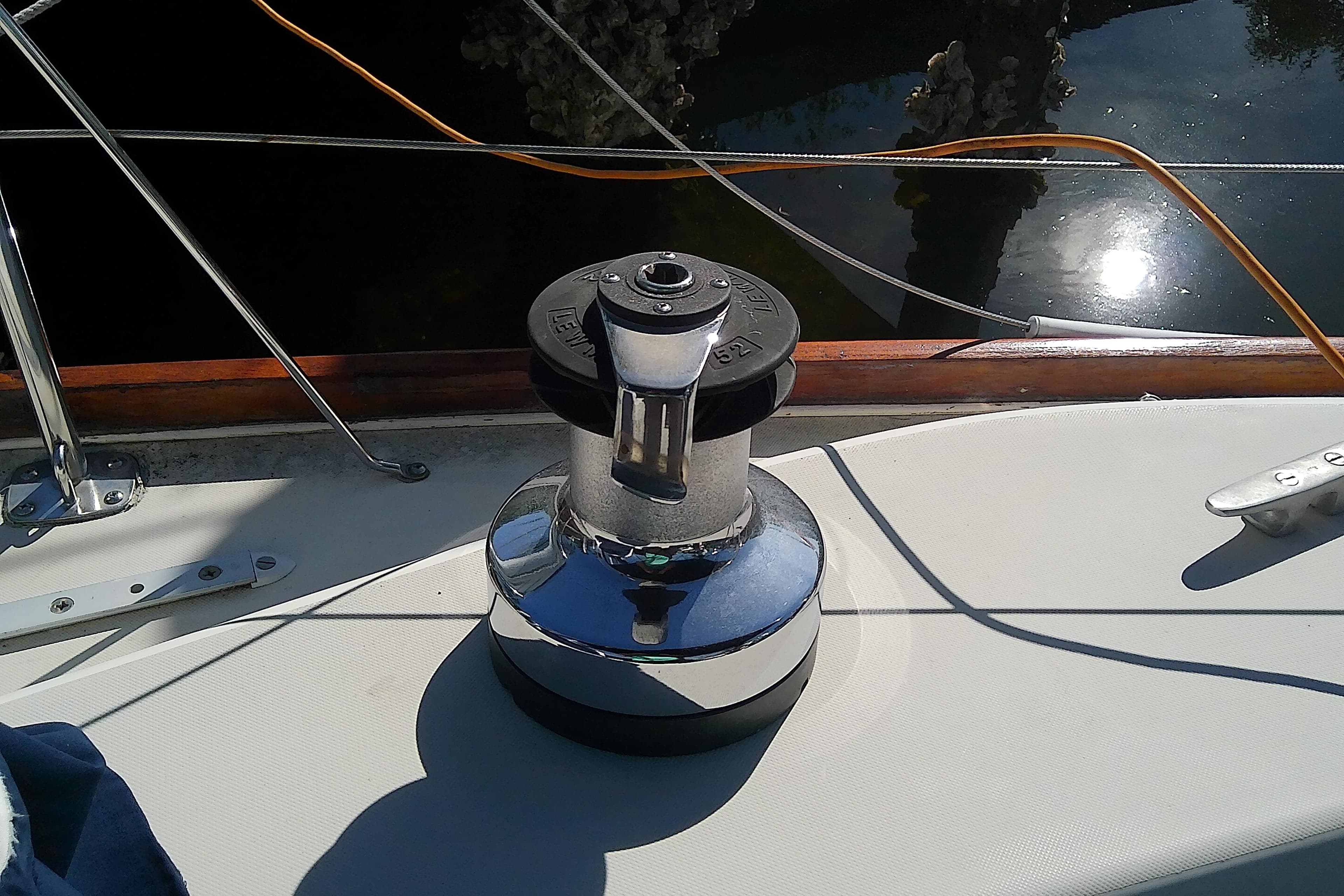 Sailboat deck with winch, Pearson 36-2, 1988 model, reflecting sunlight on water.