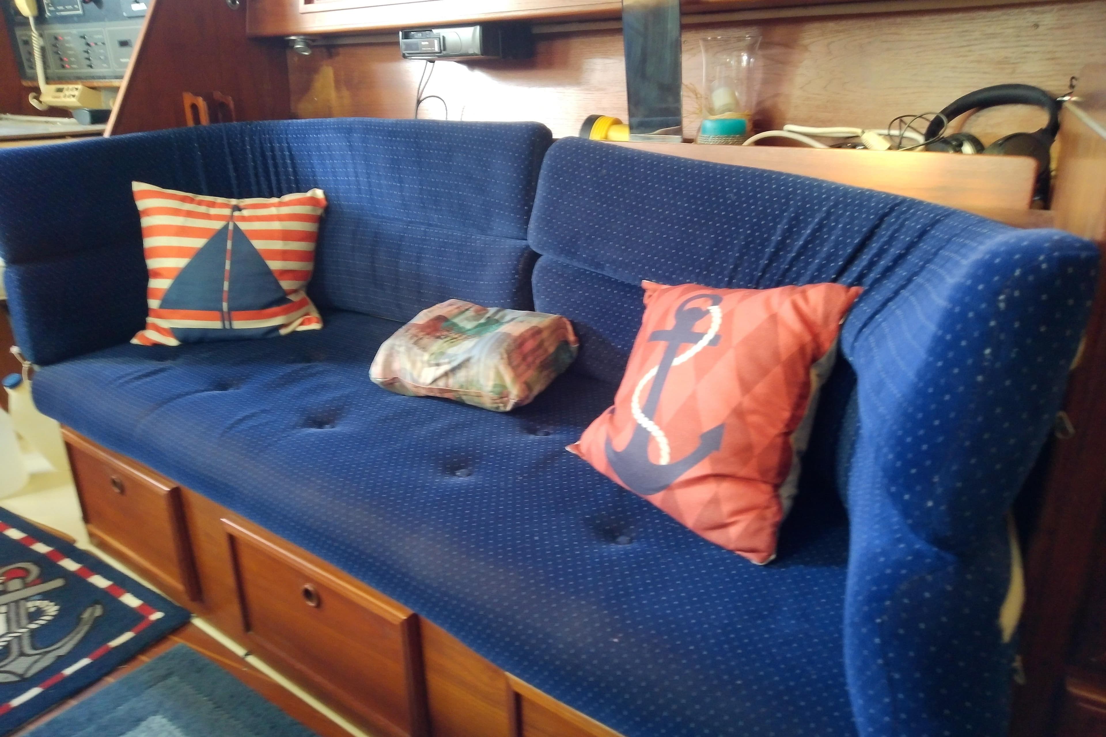 Blue cushioned seating with nautical-themed pillows on a 1988 Pearson 36-2 sailboat.
