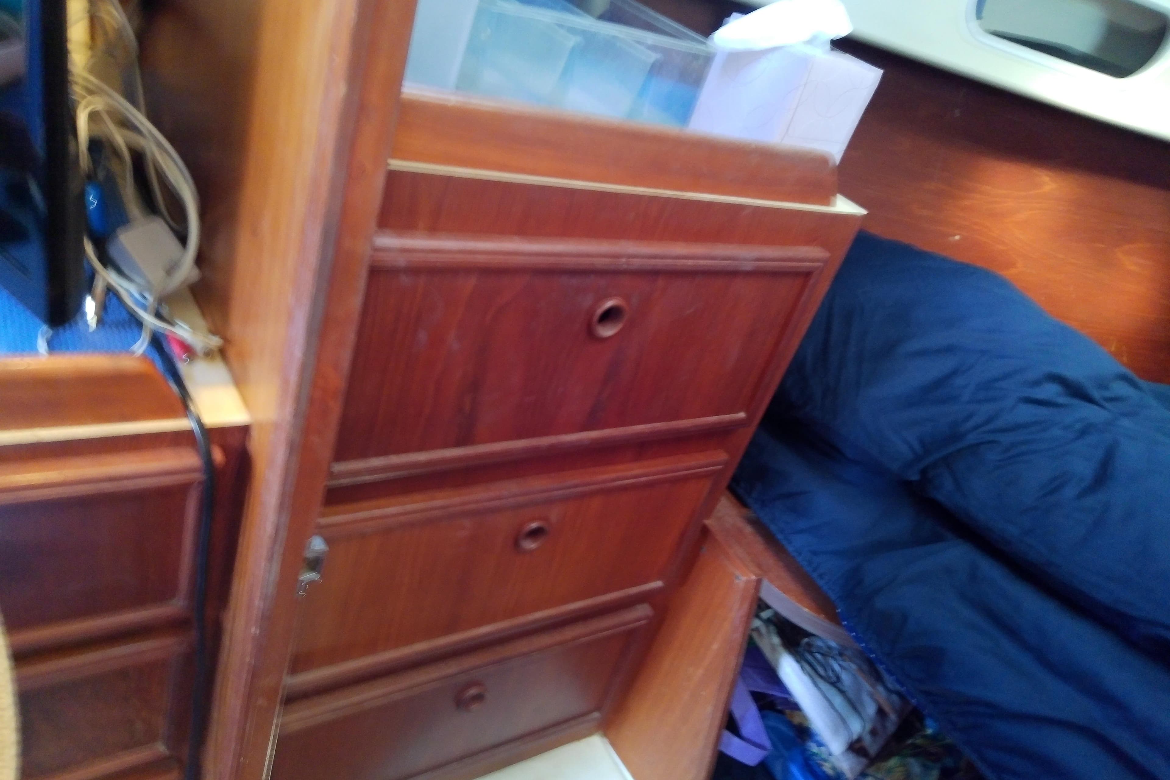 Interior of 1988 Pearson 36-2 sailboat with wooden drawers and blue bedding.
