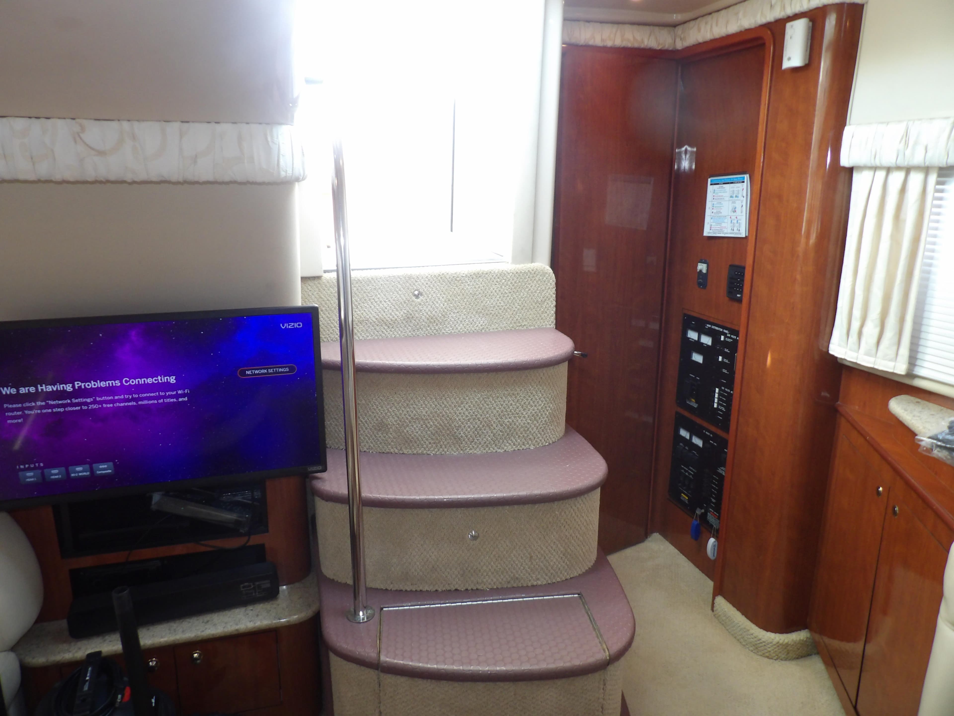 Interior of 2003 Sea Ray 390 Motor Yacht with stairs, TV, and control panel.
