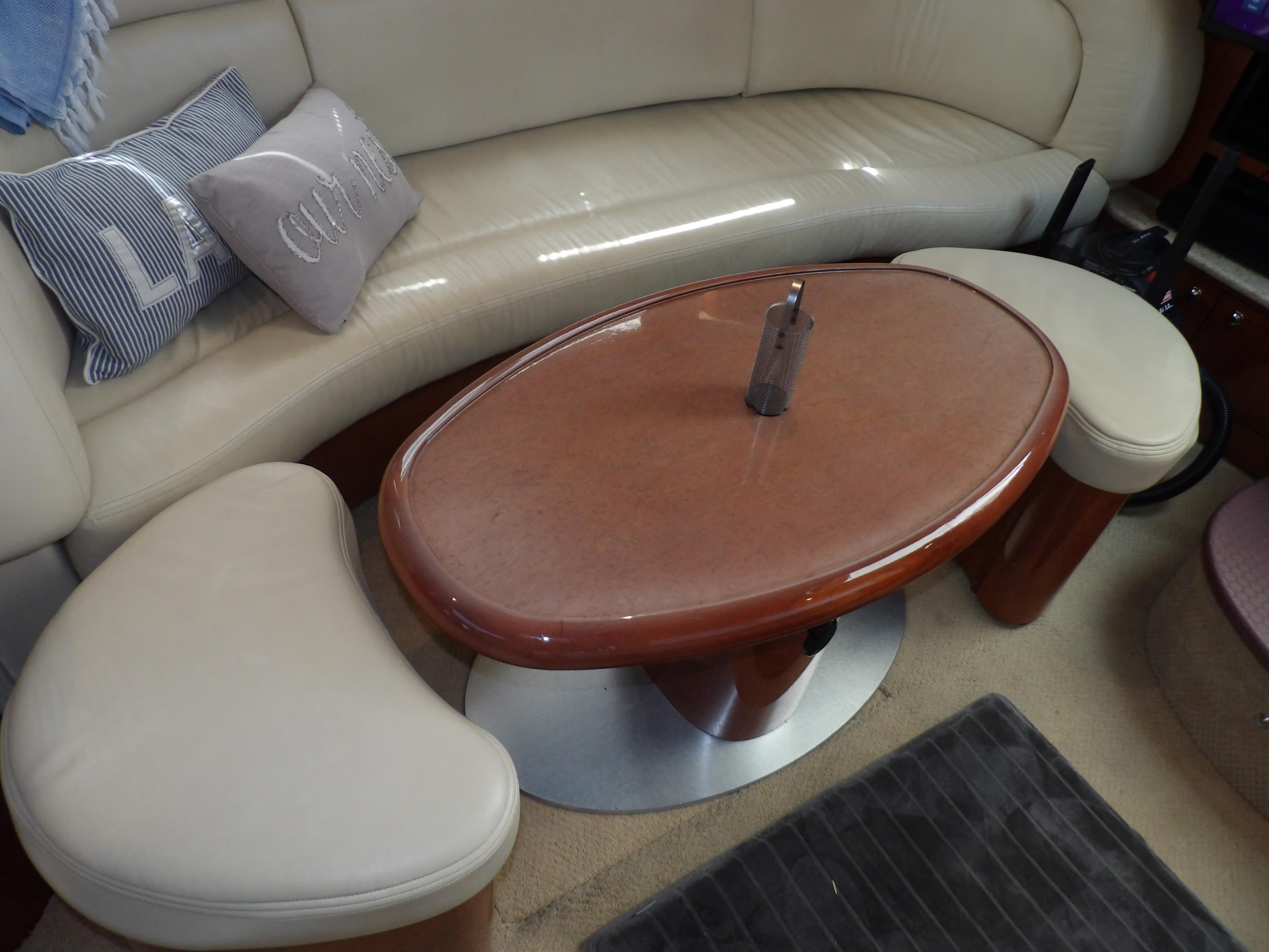 Interior seating area of 2003 Sea Ray 390 Motor Yacht with oval table and cushions.
