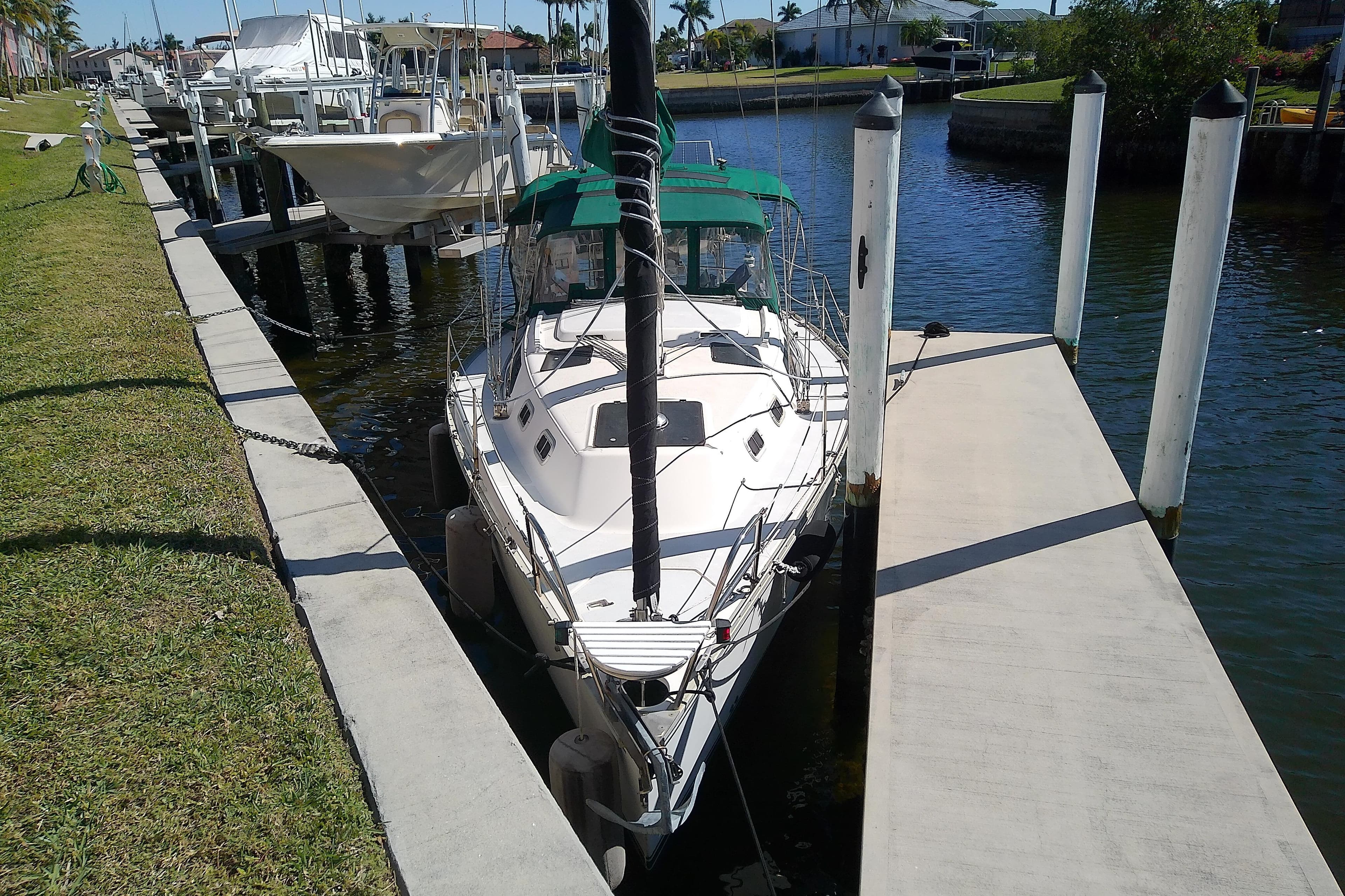 Sailboat docked at marina, 1991 Hunter 30 model, sunny day, calm water.