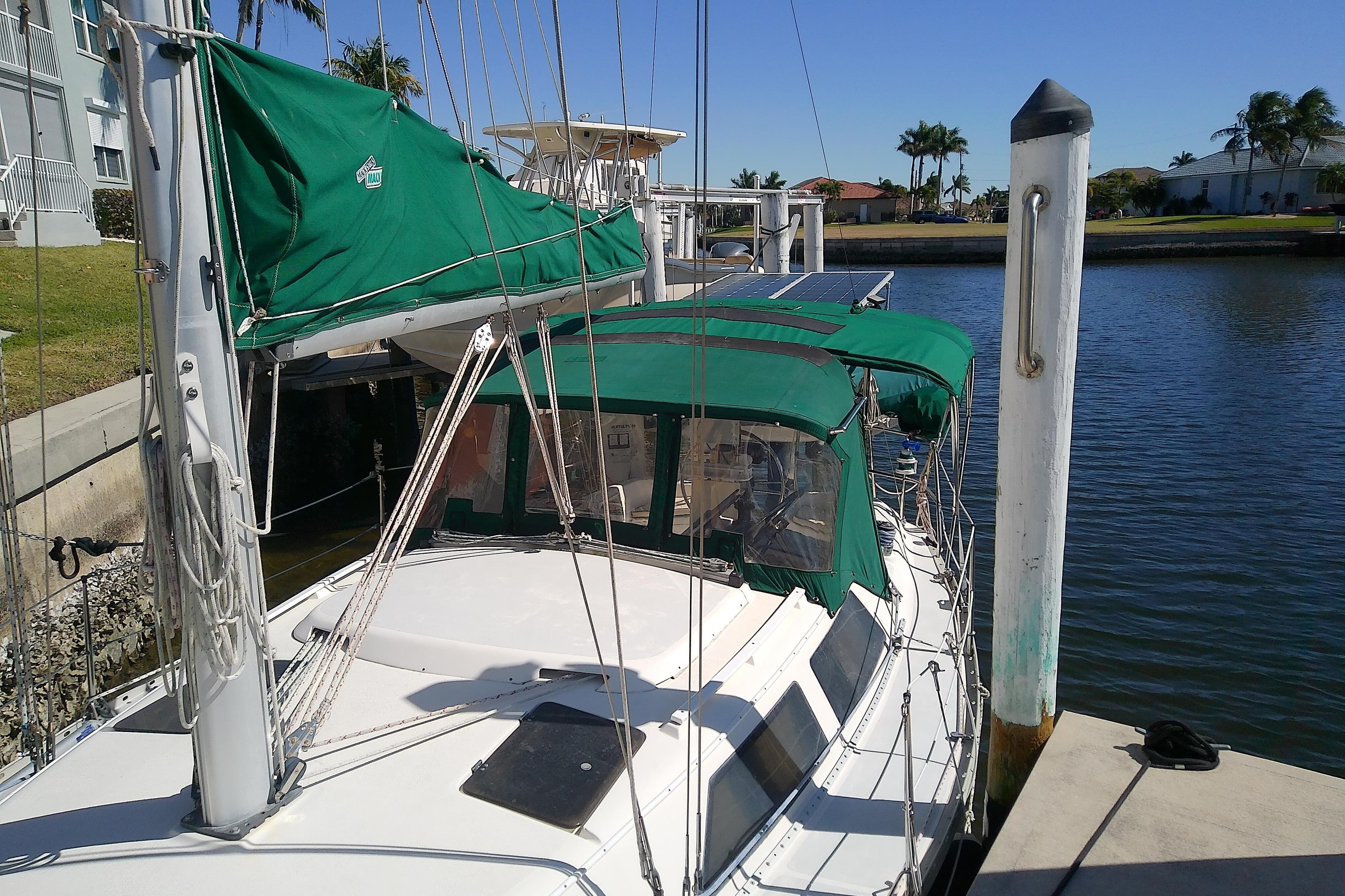 1991 Hunter 30 sailboat docked with green covers and clear skies.