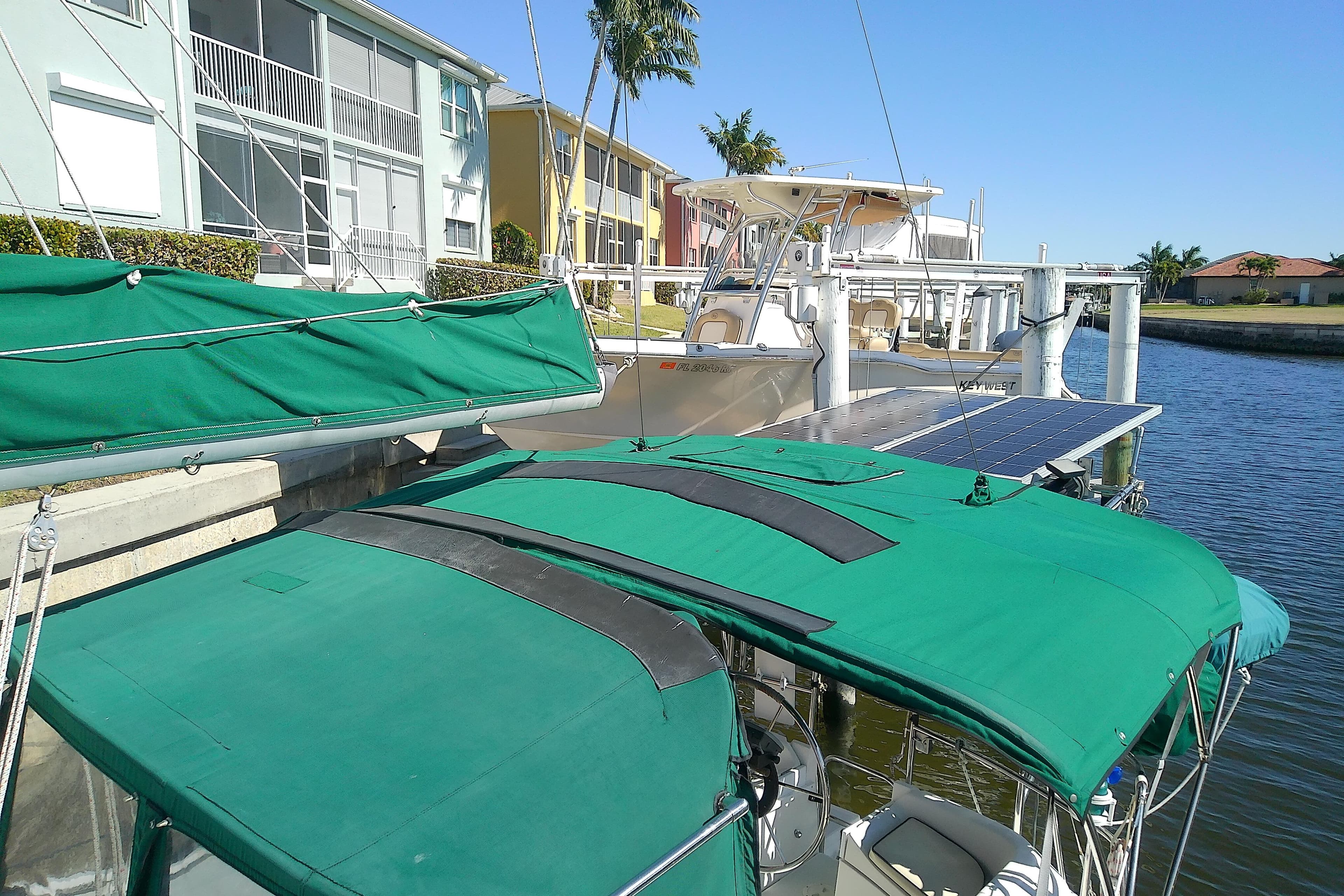 Hunter 30 sailboat from 1991 docked near waterfront homes, featuring green covers.