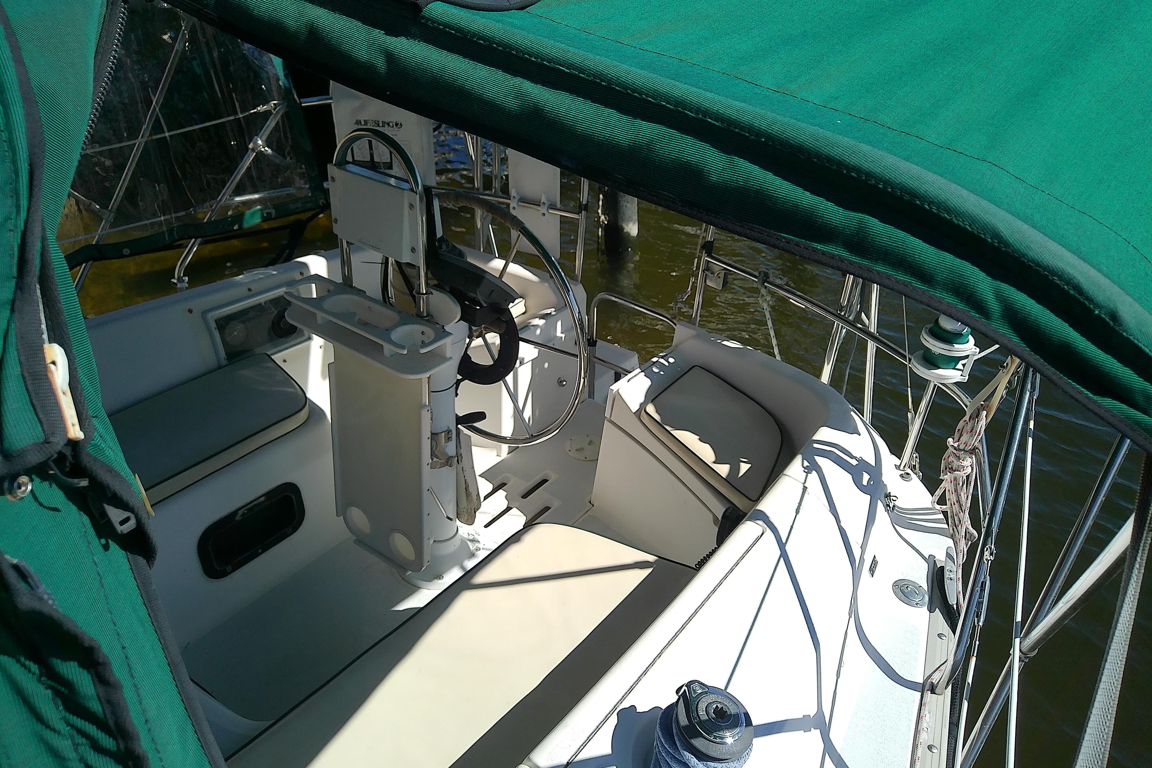 1991 Hunter 30 sailboat cockpit with green canopy and steering wheel.