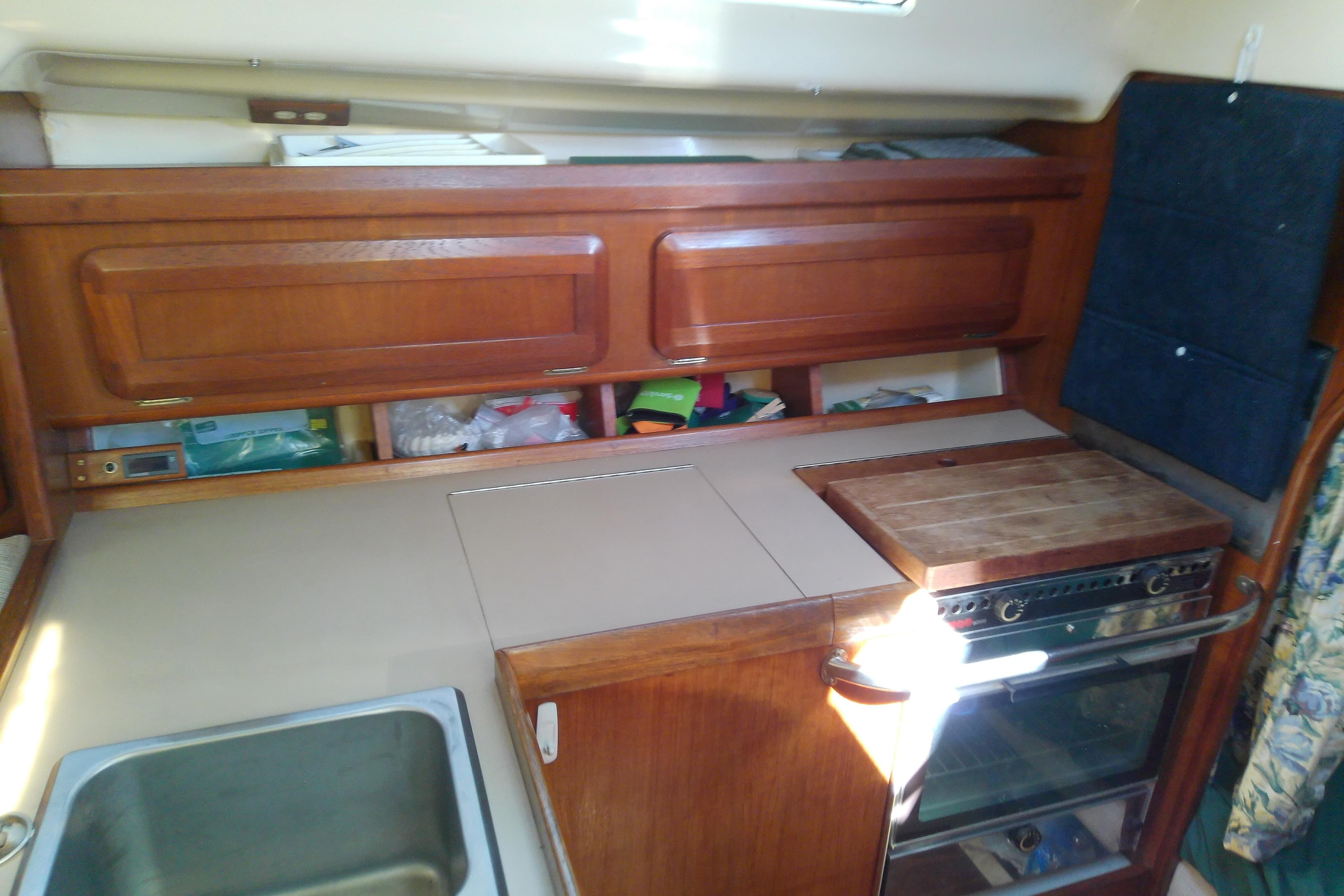 Interior of a 1991 Hunter 30 sailboat kitchen with wooden cabinets and stove.
