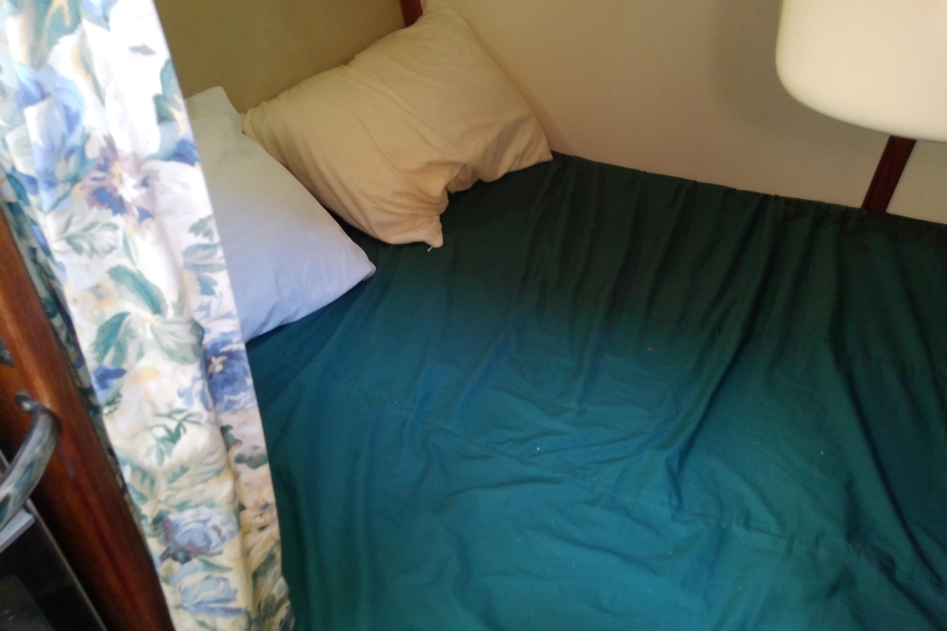 Cozy cabin bed in a 1991 Hunter 30 sailboat with floral curtain.