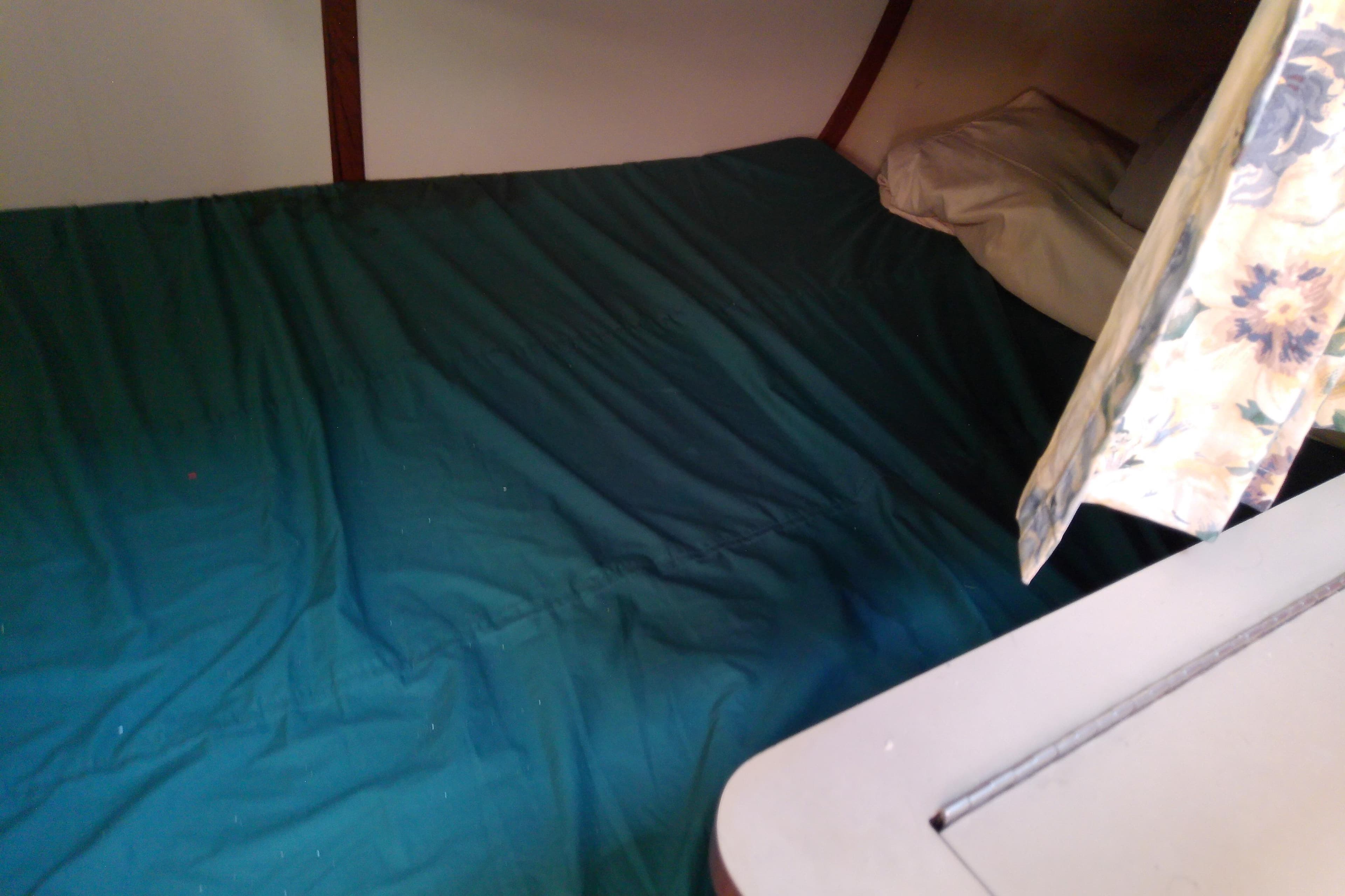 Interior cabin of 1991 Hunter 30 sailboat with bed and floral curtain.