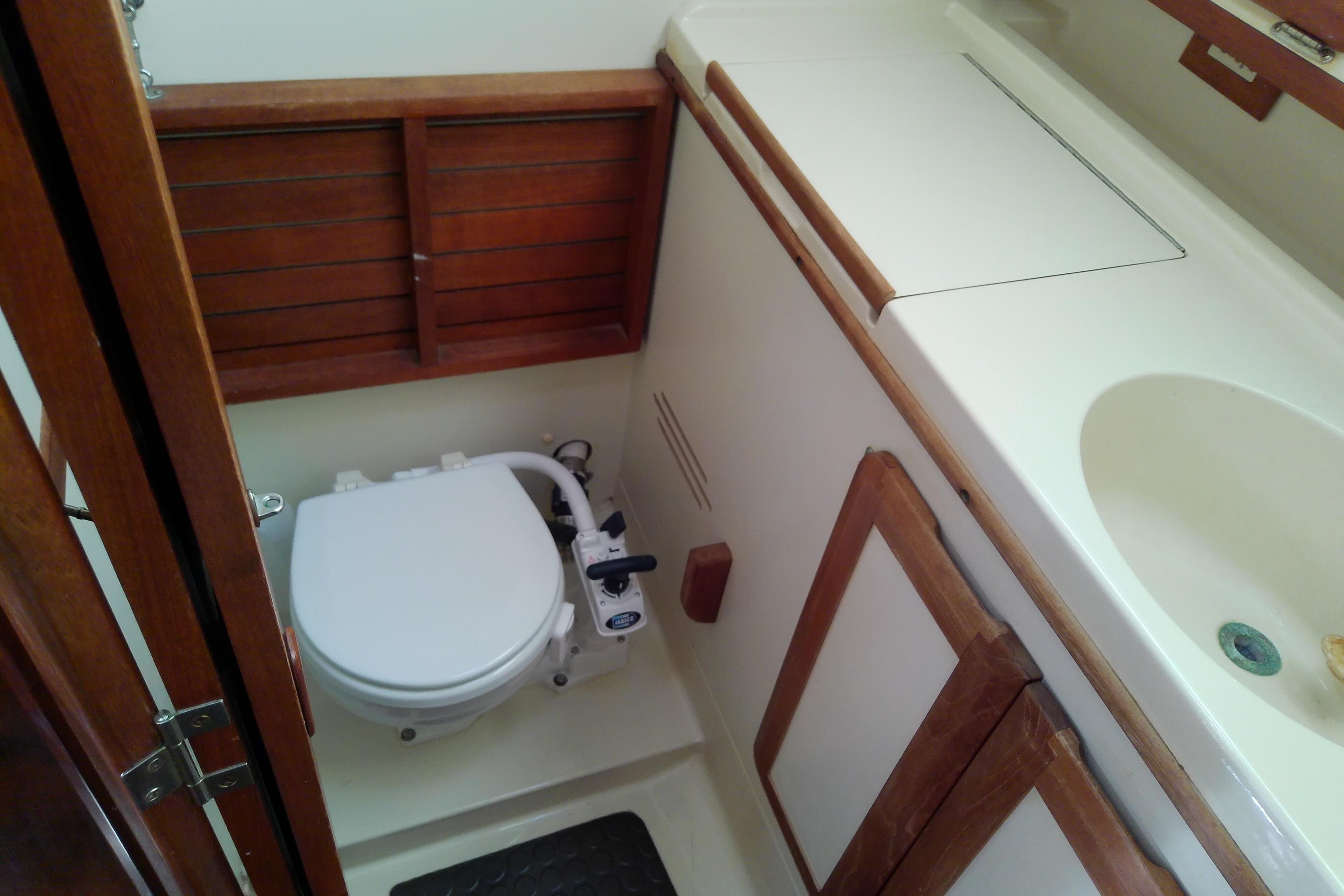 1991 Hunter 30 sailboat bathroom with toilet, sink, and wooden cabinetry.