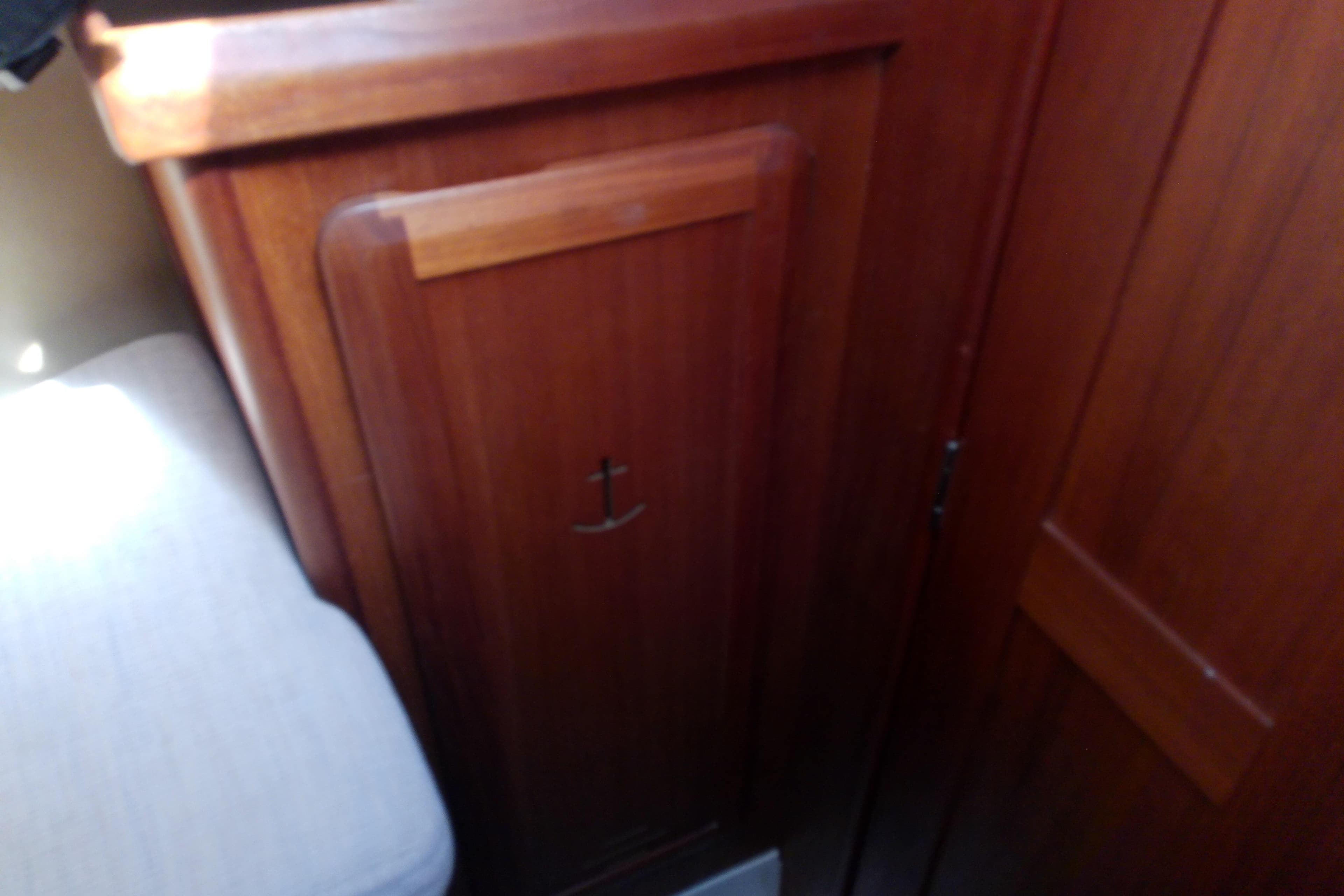 Wooden interior of a 1991 Hunter 30 sailboat with anchor emblem on cabinet.