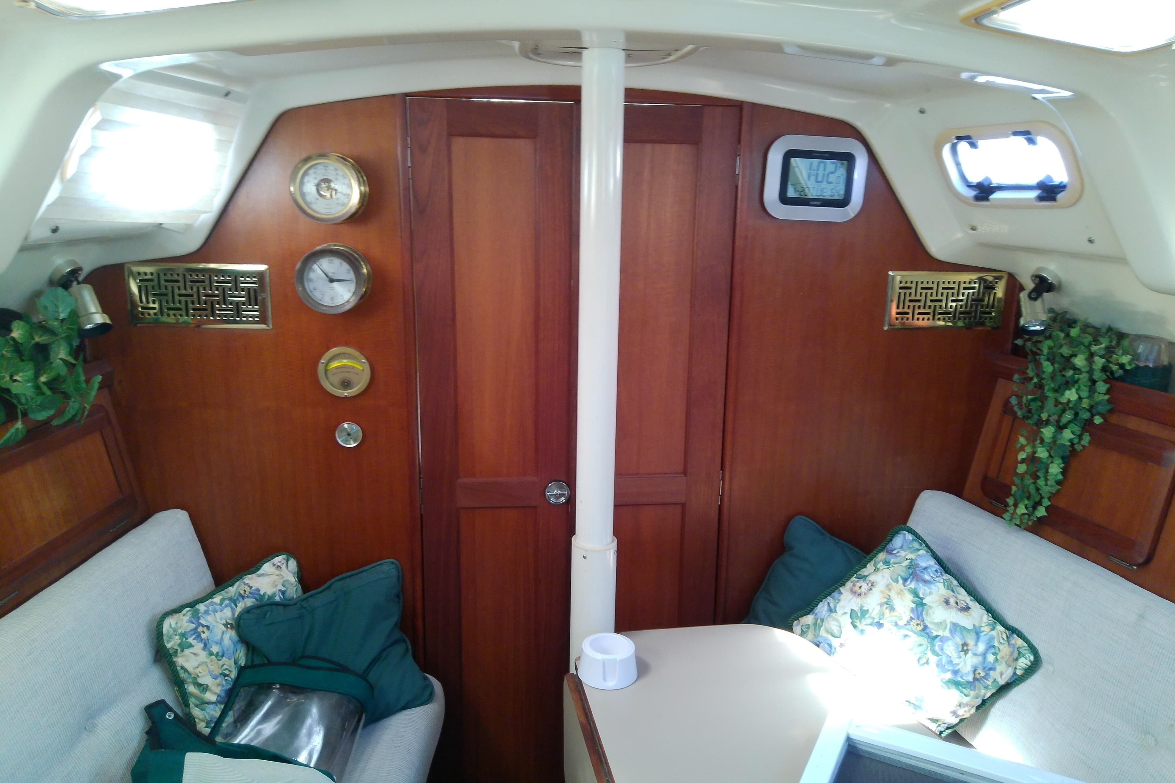 Interior of a 1991 Hunter 30 sailboat with wood paneling and cozy seating.