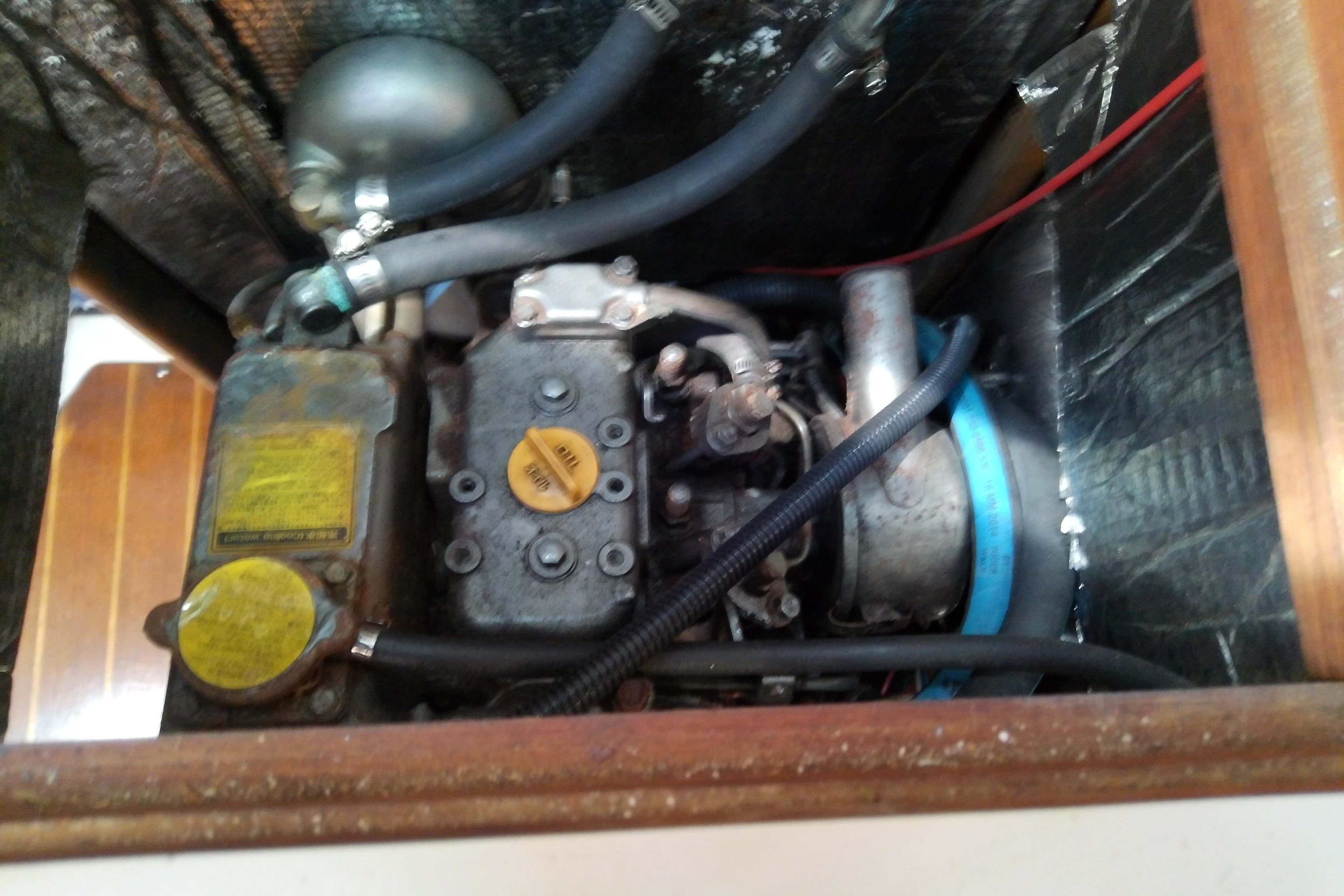 Engine compartment of a 1991 Hunter 30 sailboat, showing mechanical components and hoses.
