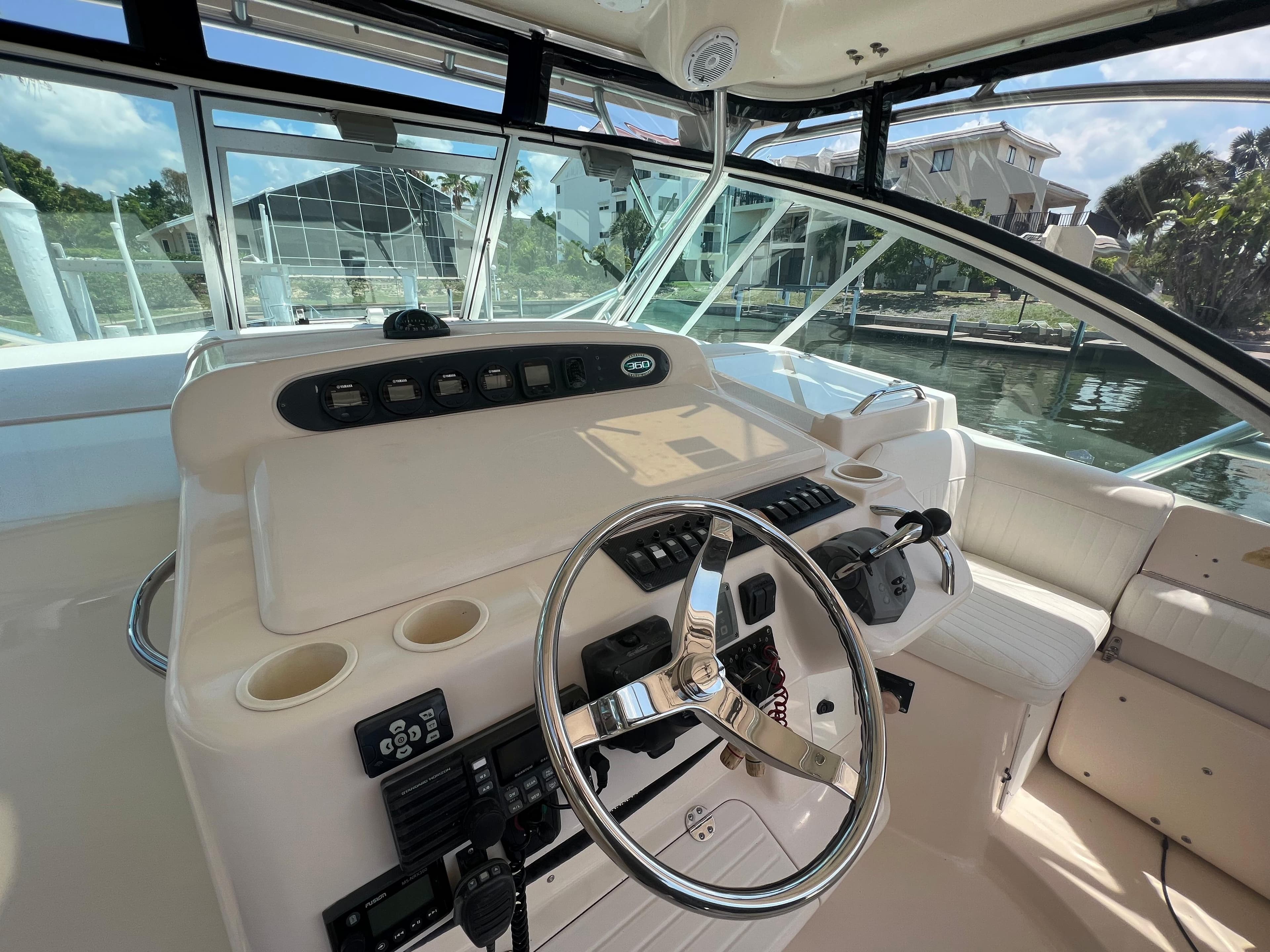 2006 Grady-White 360 Express helm with steering wheel and control panel, docked by waterfront homes.
